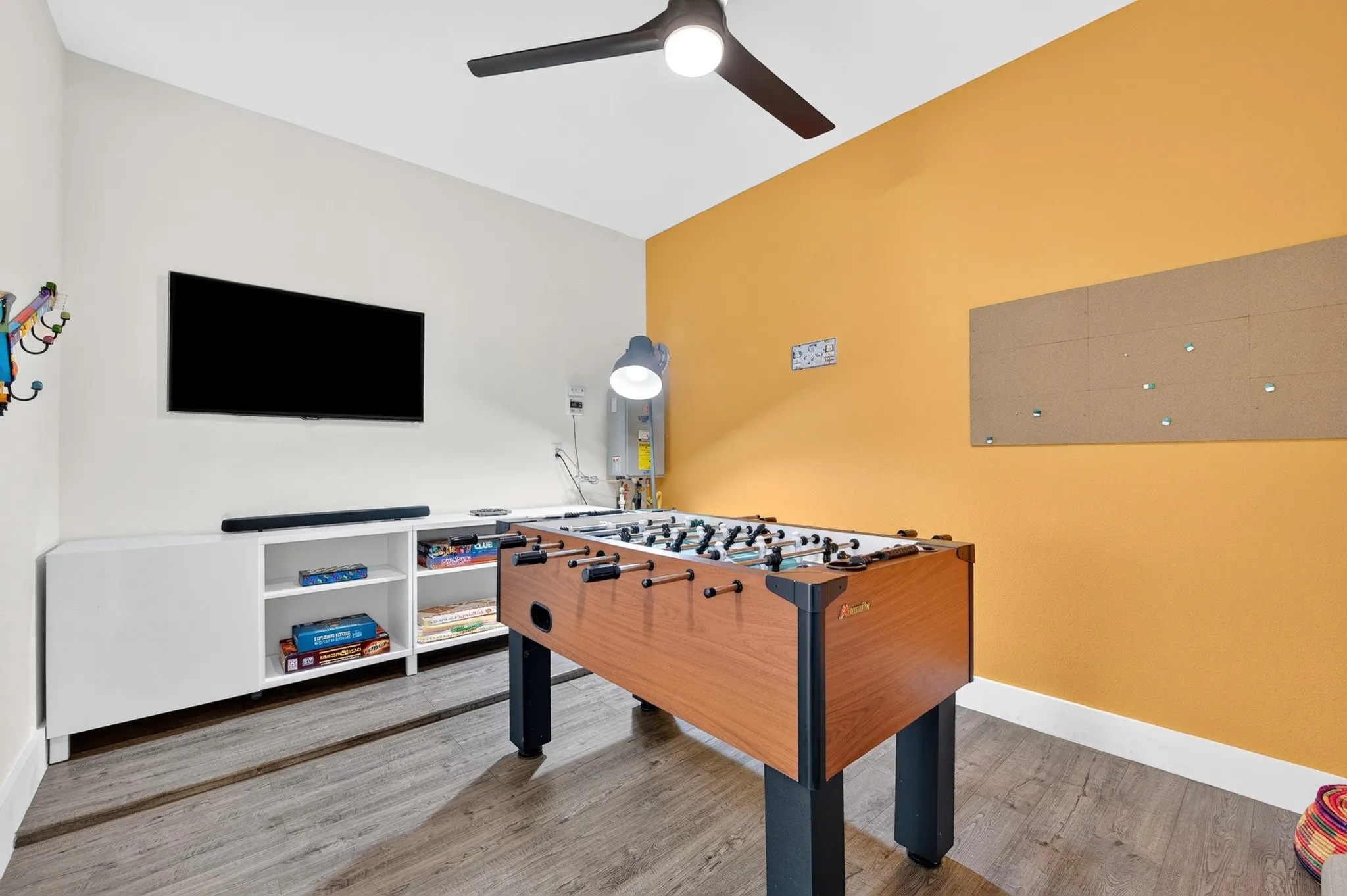 Entertainment space featuring wood-finish flooring, a contemporary ceiling fan, and built-in shelving