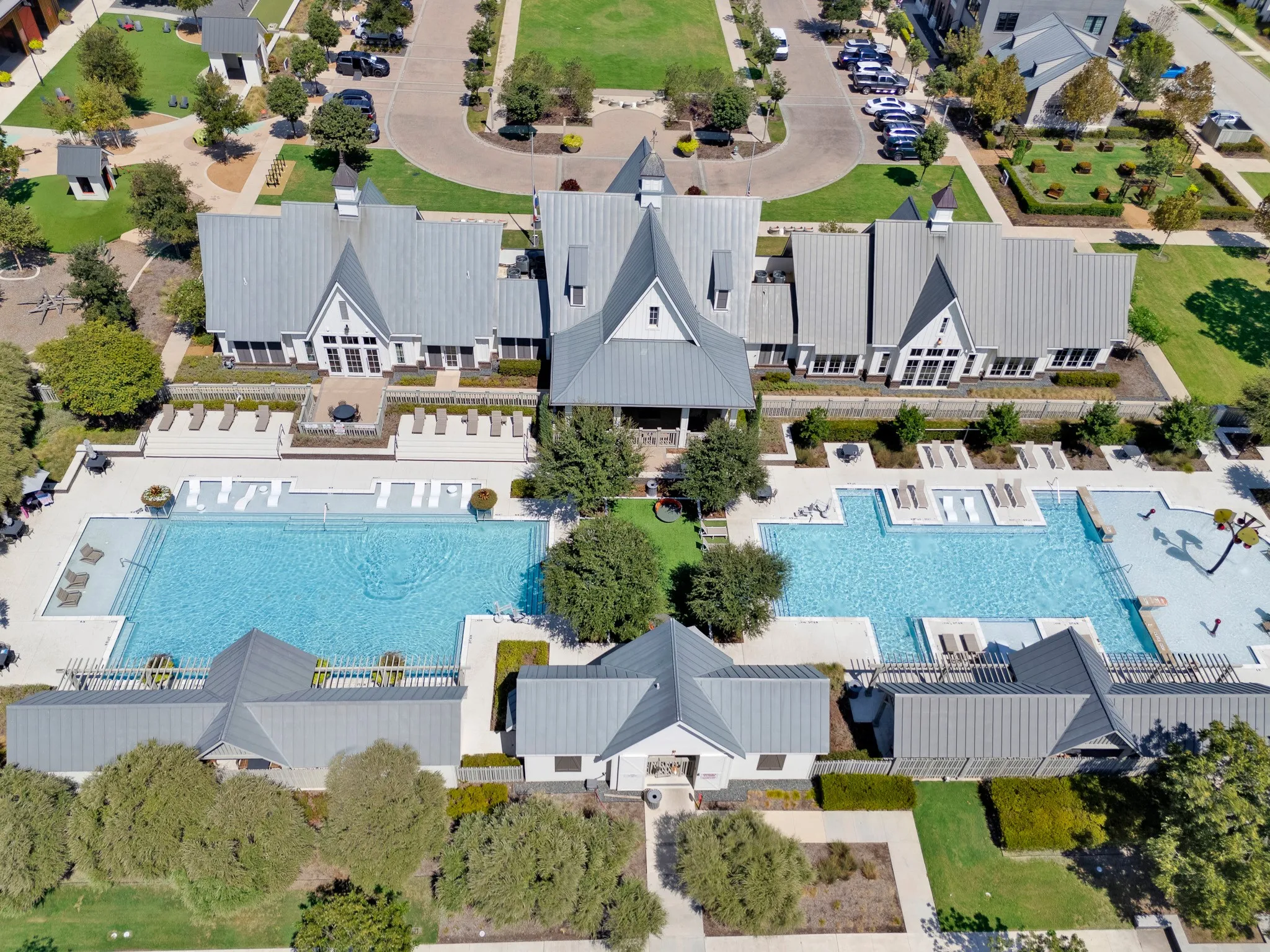 Expansive community pool area featuring a large rectangular pool, a curved pool, and multiple lounge areas