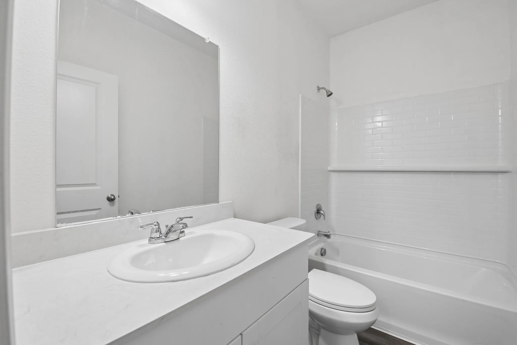 Hallway bathroom with cultured marble counter and wood look LVP flooring.