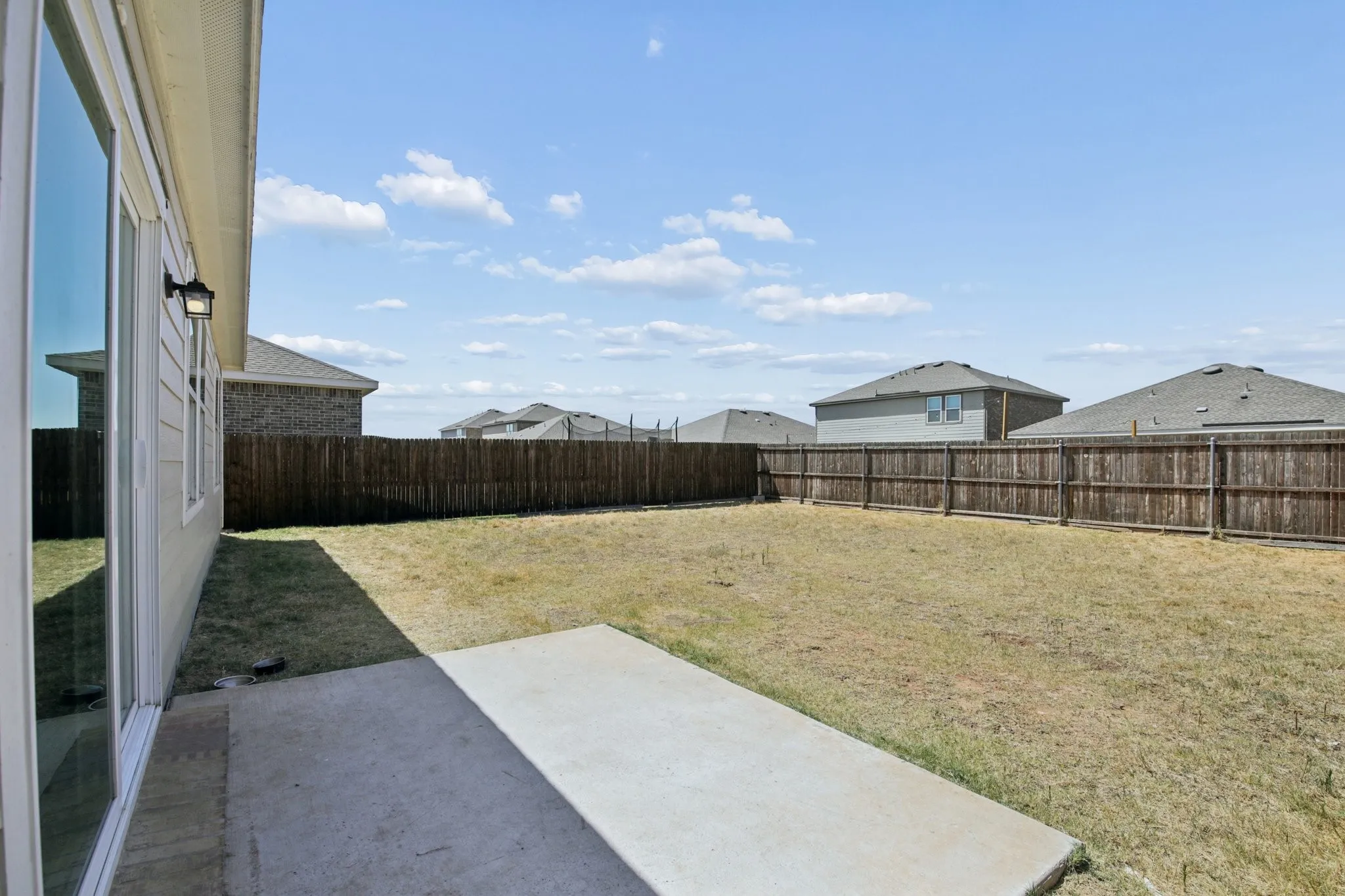 Large yard with concrete patio off of the dining room.