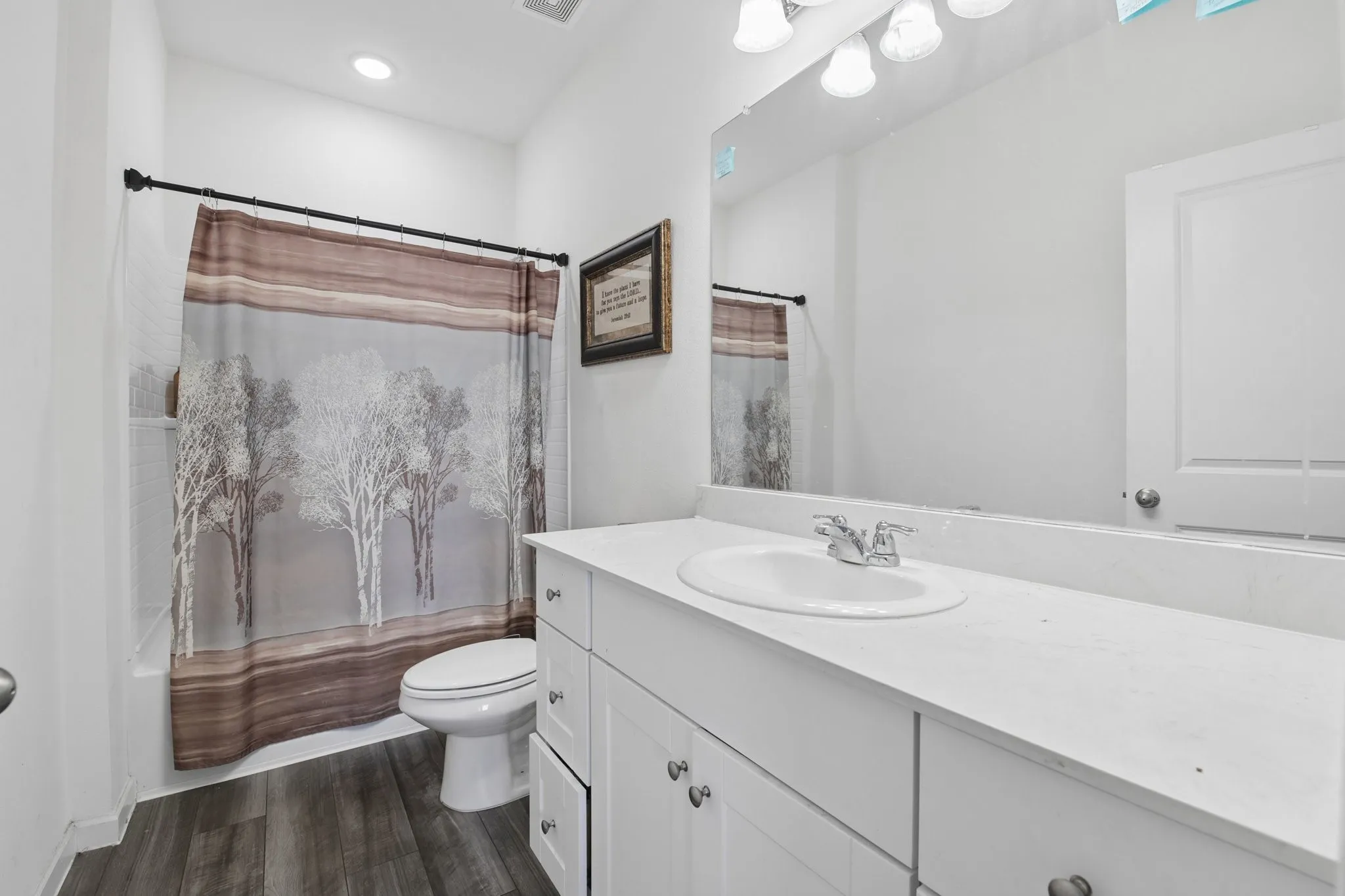 Primary bathroom with cultured marble counter, has wood look plank flooring and shower tub combo.