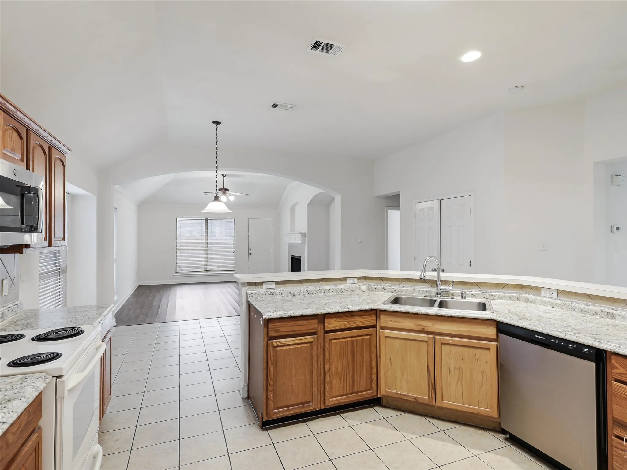 Kitchen featuring light wood-finish cabinetry, light granite-style countertops, stainless steel appliances, and a dual basin sink