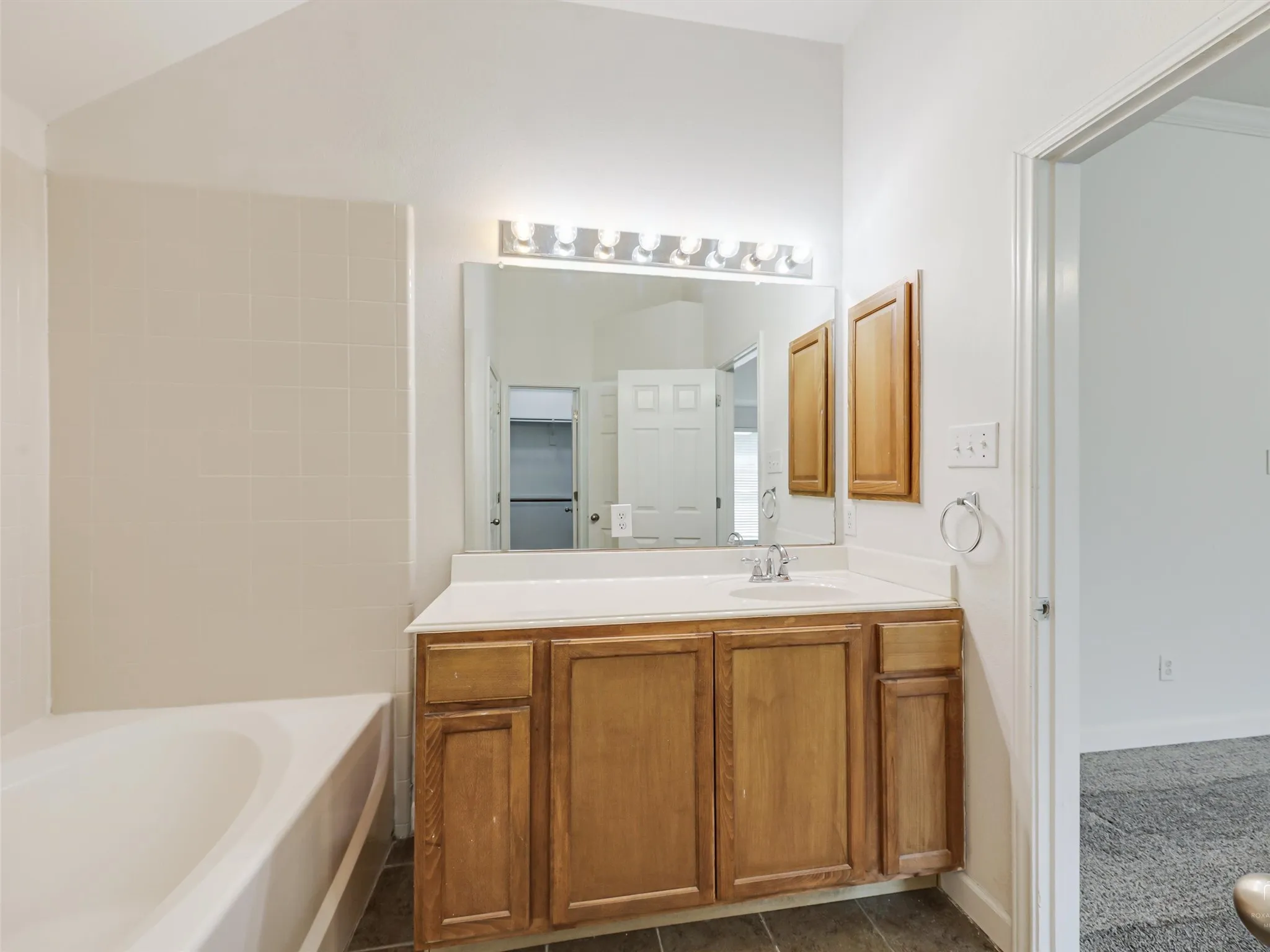 Bathroom featuring a single vanity with wood cabinetry, a white countertop, and a large mirror