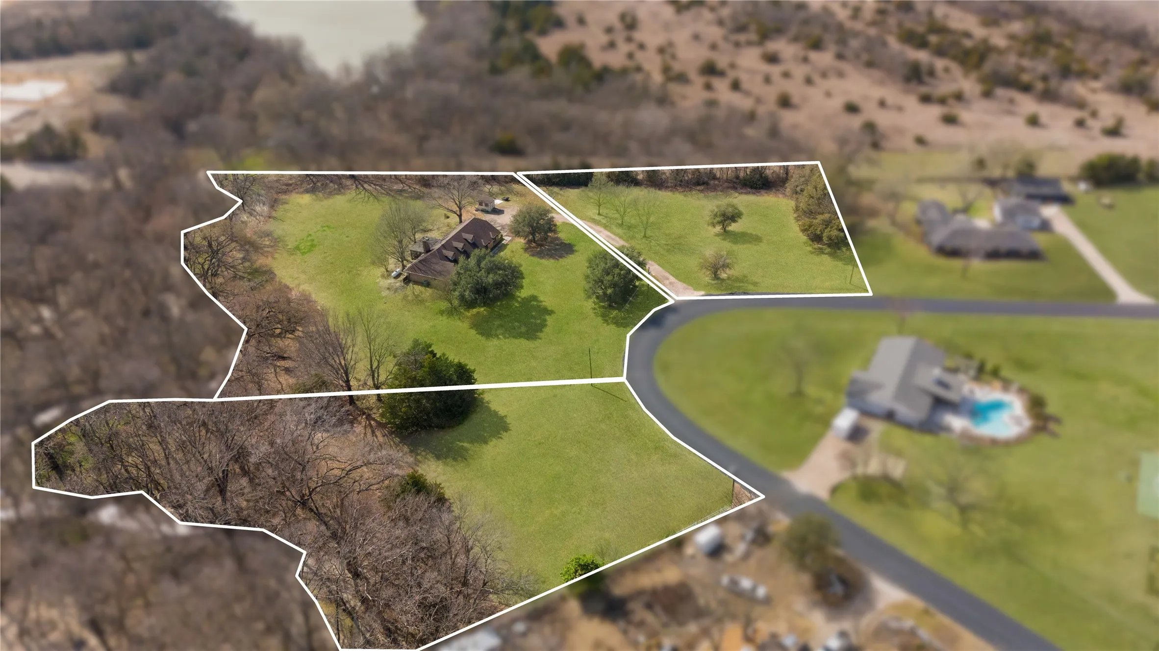Expansive green acreage with a visible dwelling and surrounding mature trees