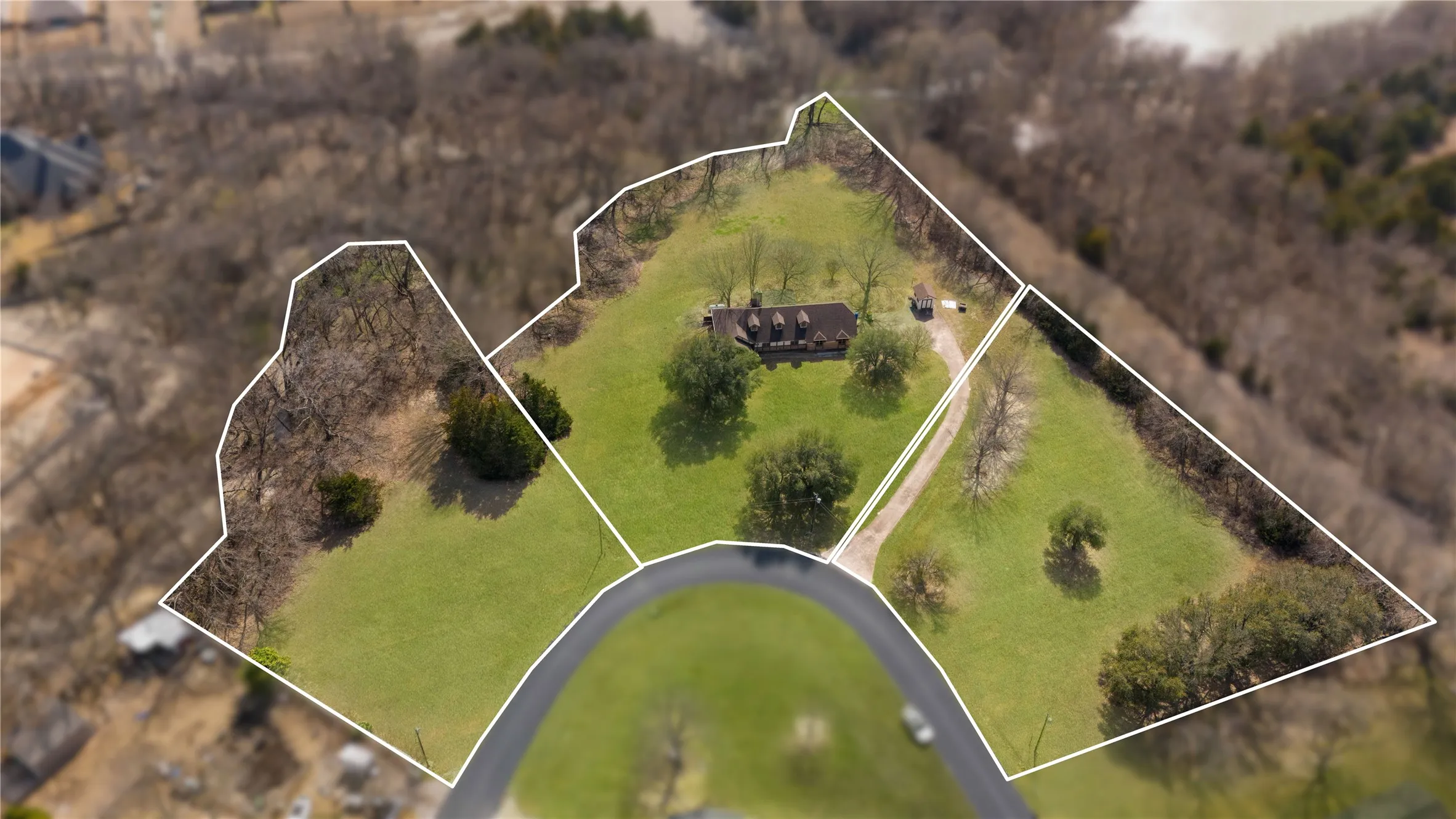 Expansive property featuring verdant lawns, mature trees, a private driveway, and a residential structure