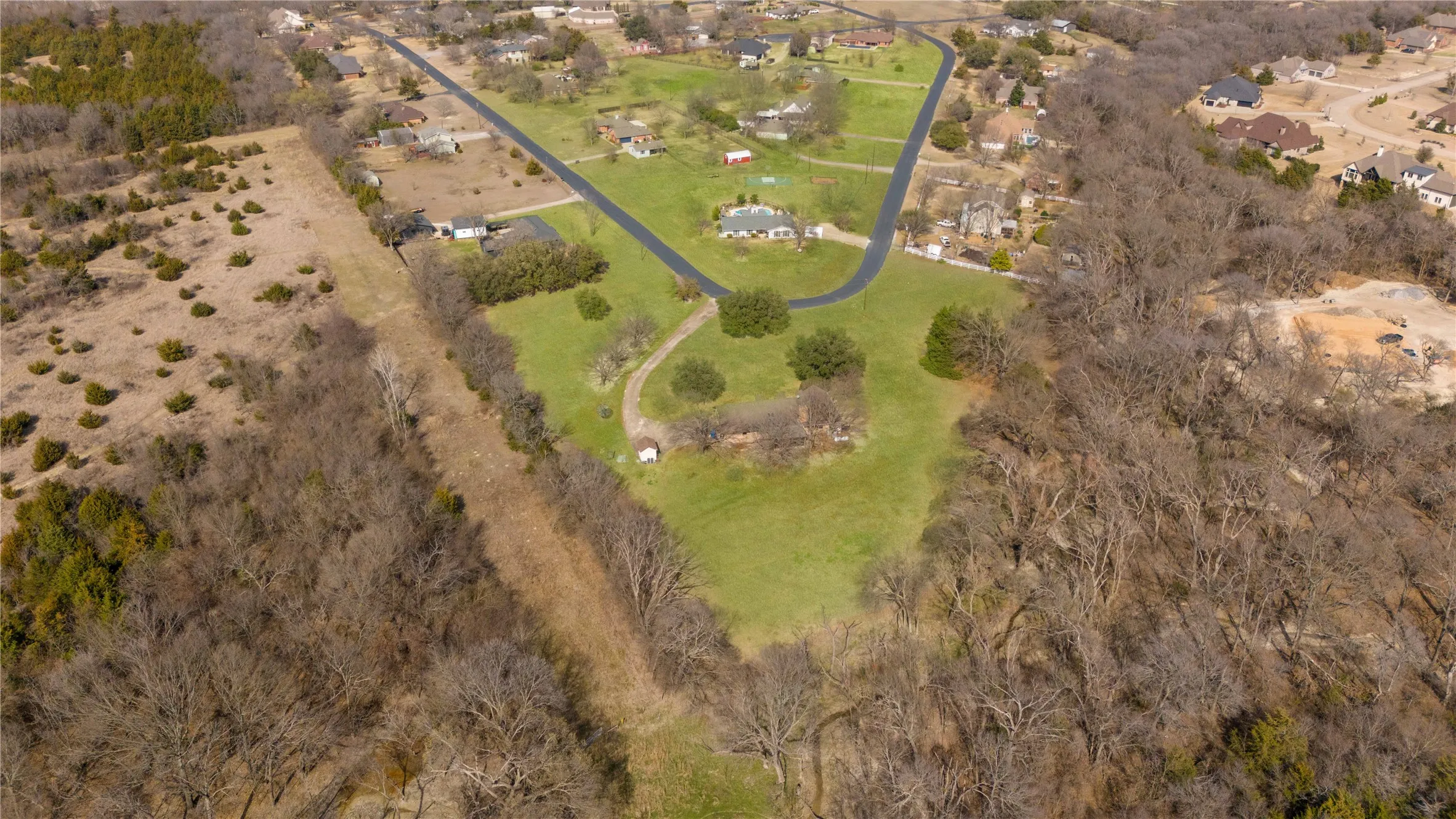 Sprawling rural estate set on manicured grounds with mature tree-lined perimeter, curved driveway approach, and multiple residential structures nestled within lush acreage