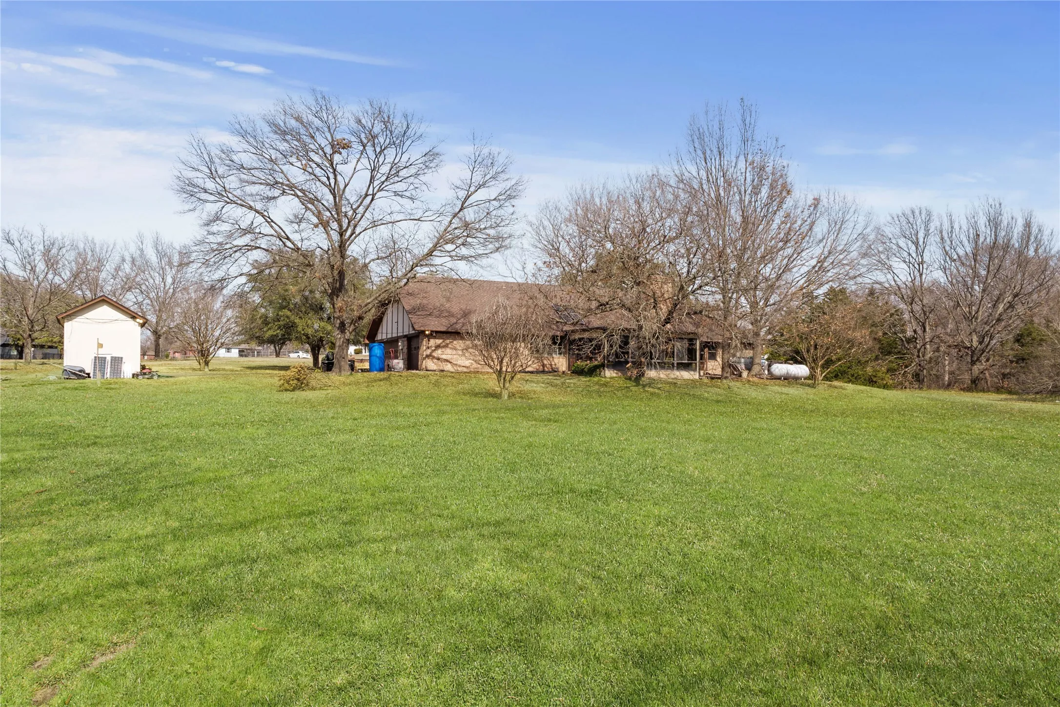 Expansive green lawn with mature trees and a detached structure