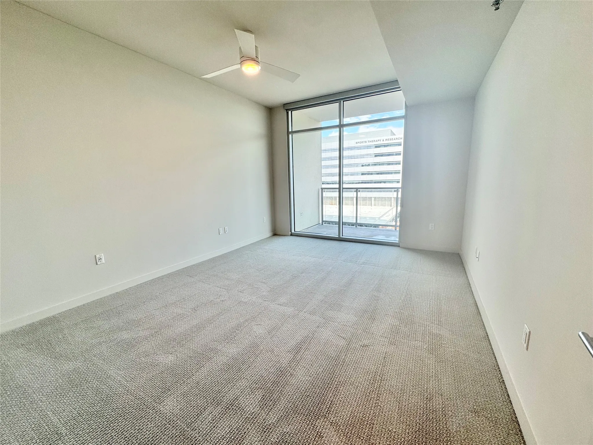 Spare room with light carpet, expansive windows, and ceiling fan