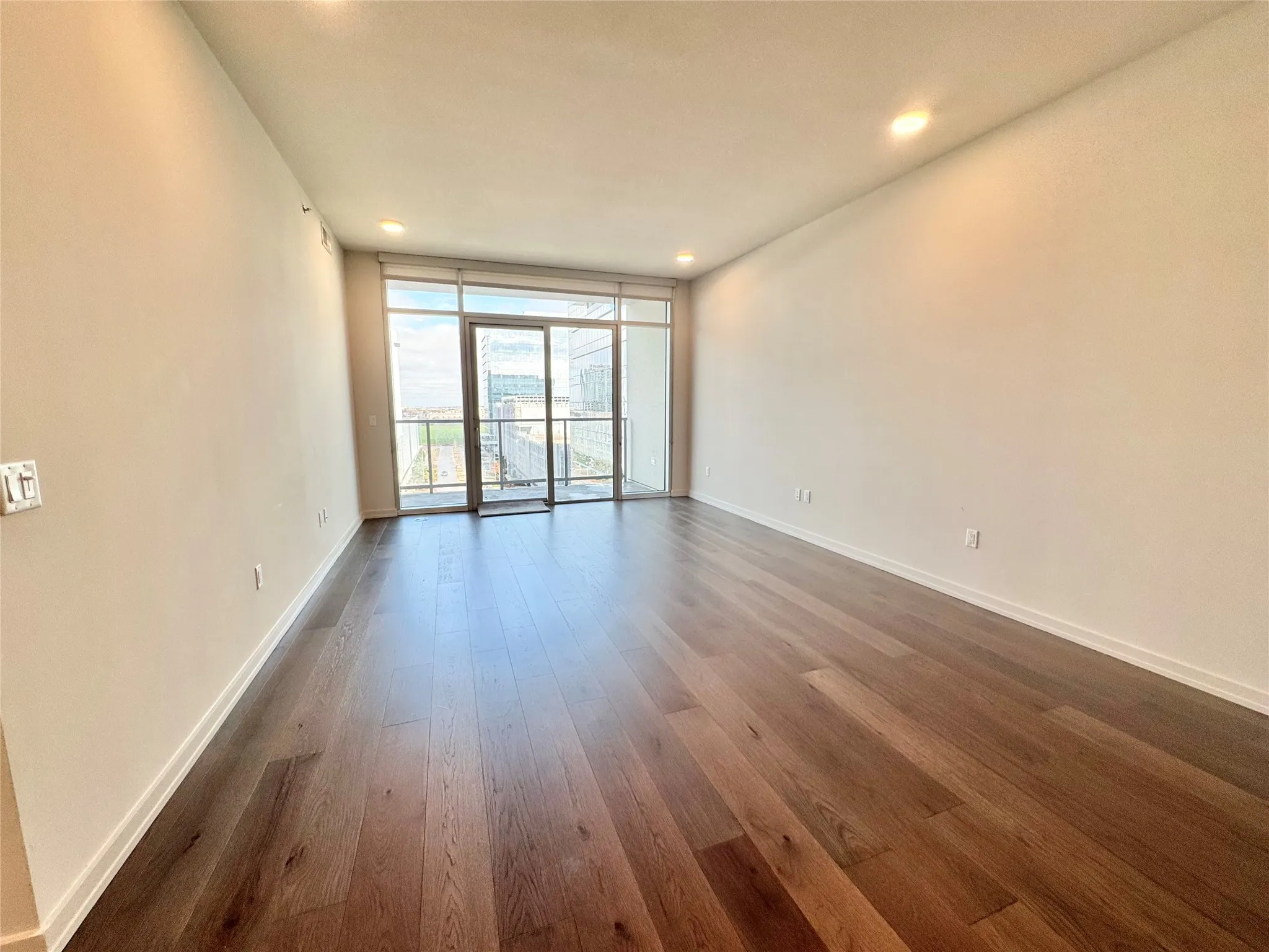 Empty room featuring expansive windows and dark hardwood / wood-style flooring