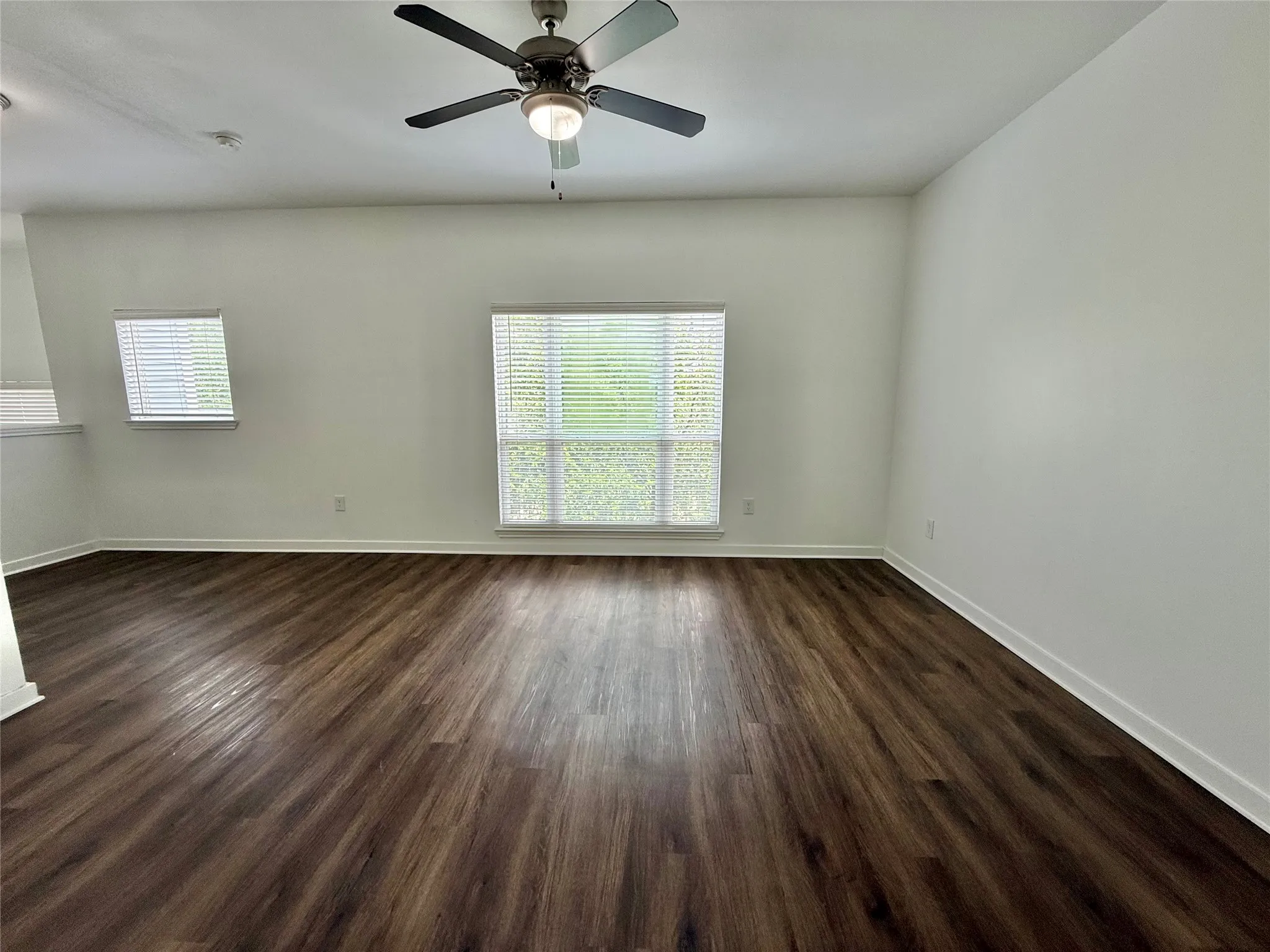 Spare room with plenty of natural light, dark wood finished floors, and baseboards