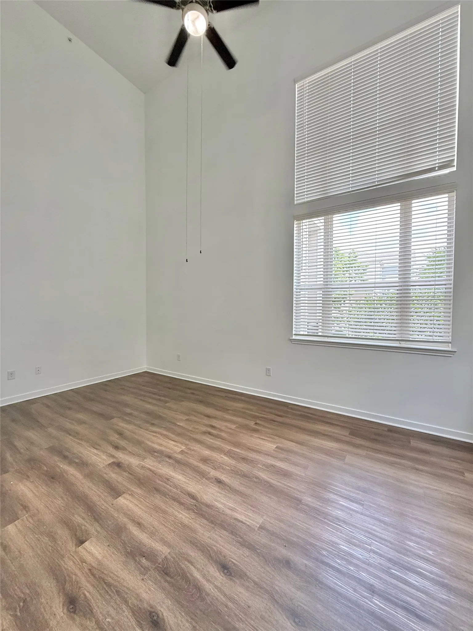 Empty room with a ceiling fan, baseboards, and wood finished floors