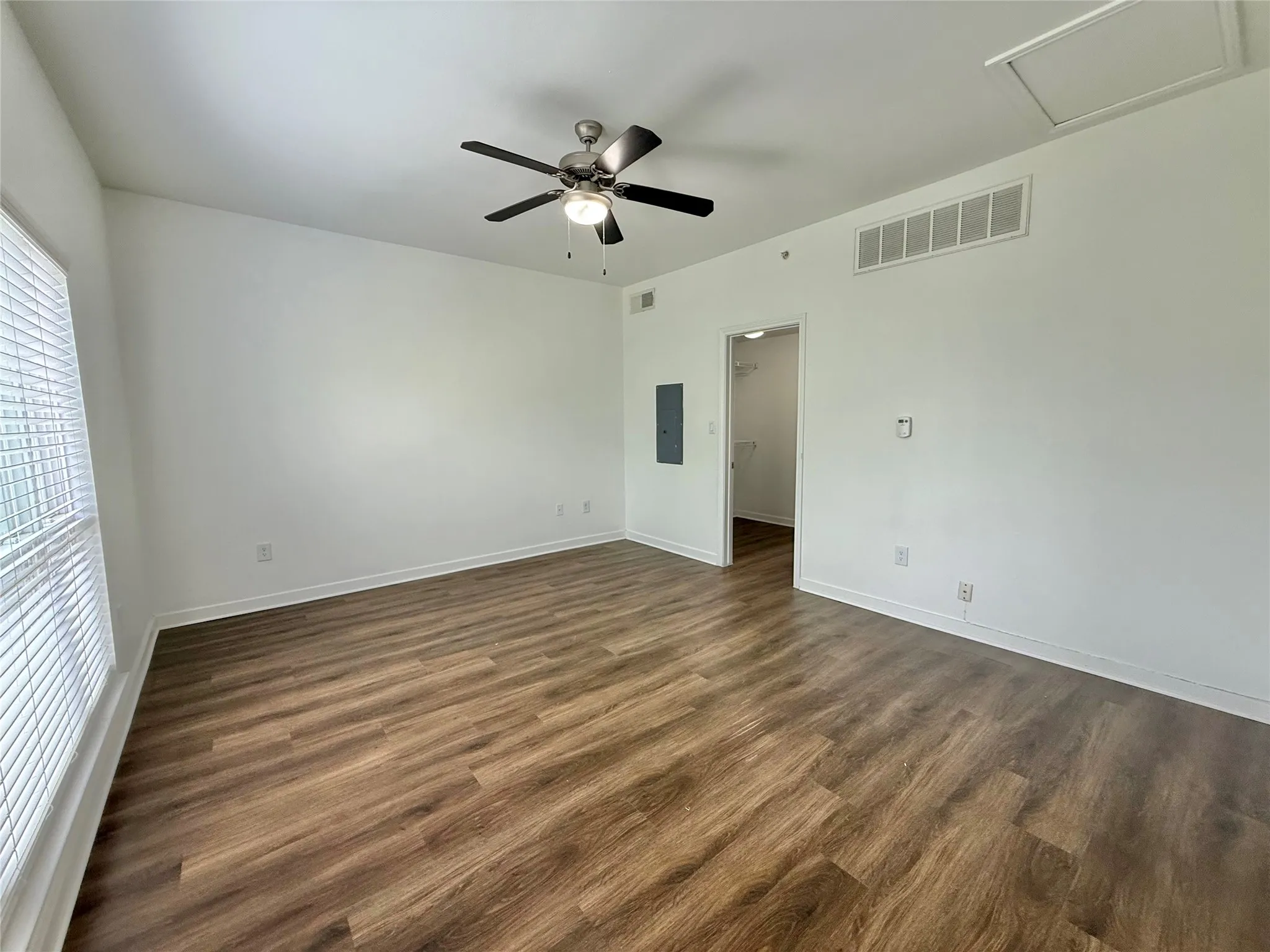 Spare room with dark wood-type flooring, a ceiling fan, baseboards, and electric panel