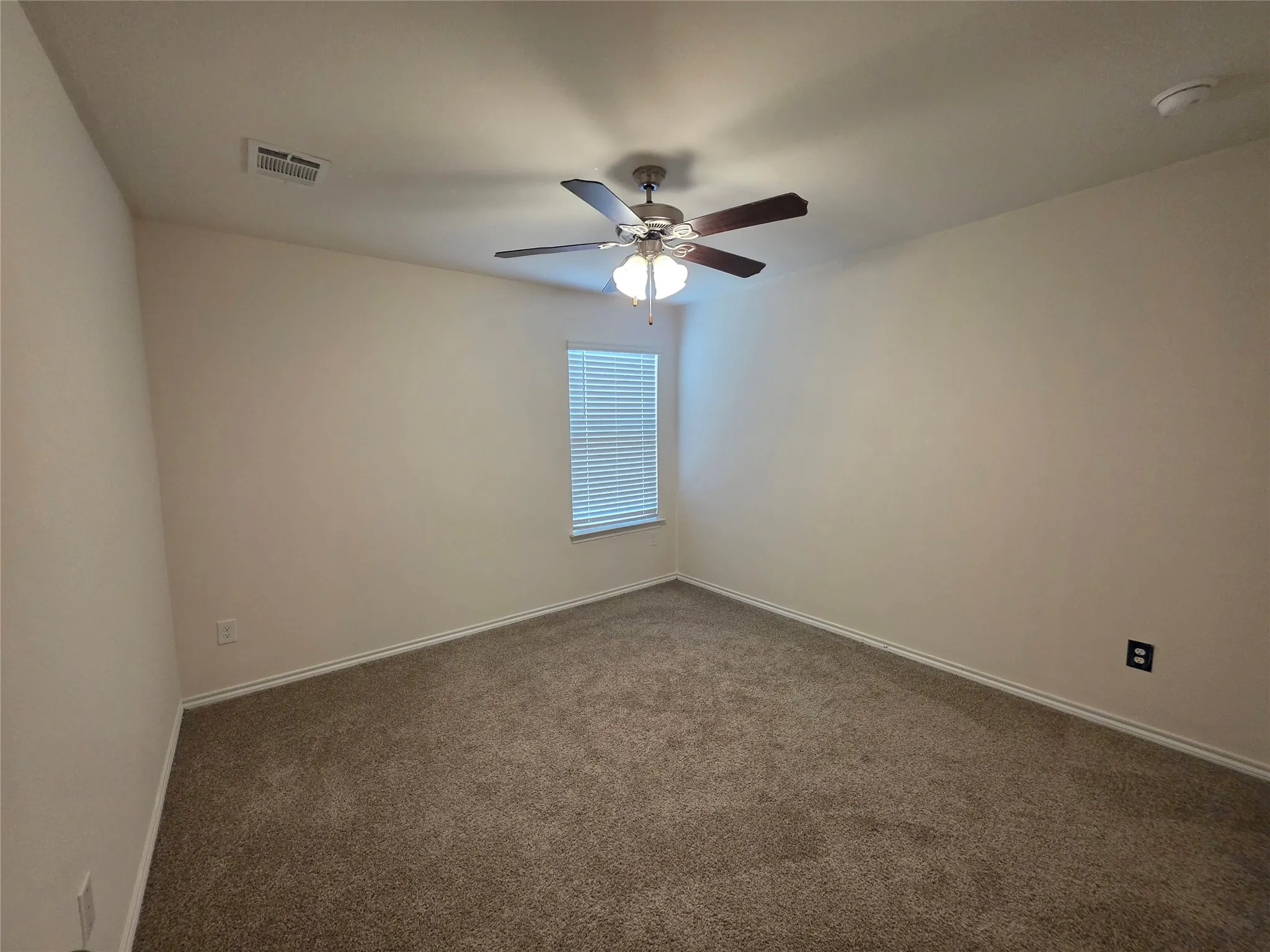 Carpeted room featuring a ceiling fan with integrated lighting, a window with blinds, and light-colored walls