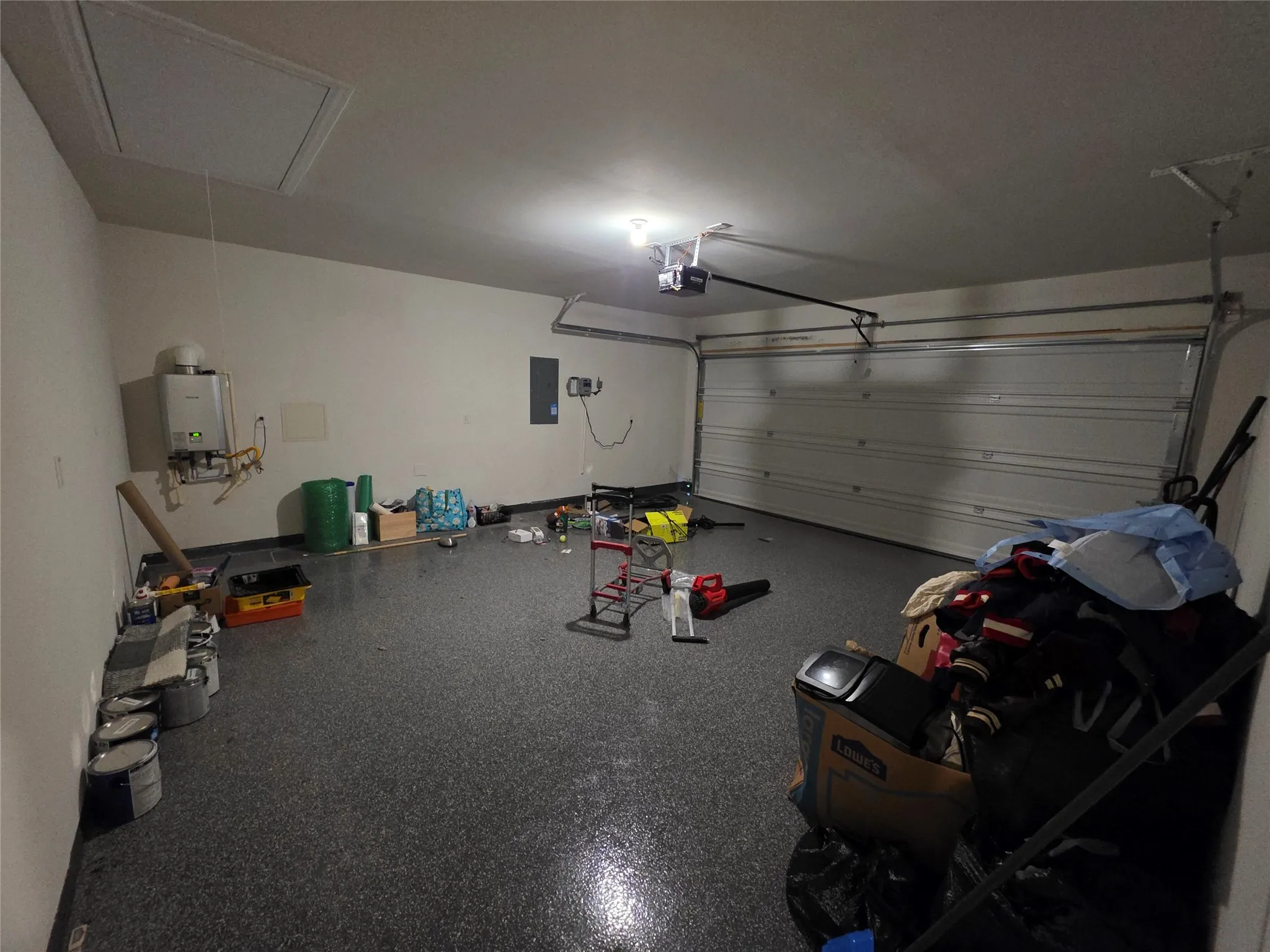 Garage featuring an overhead door, speckled epoxy flooring, and a ceiling-mounted garage door opener