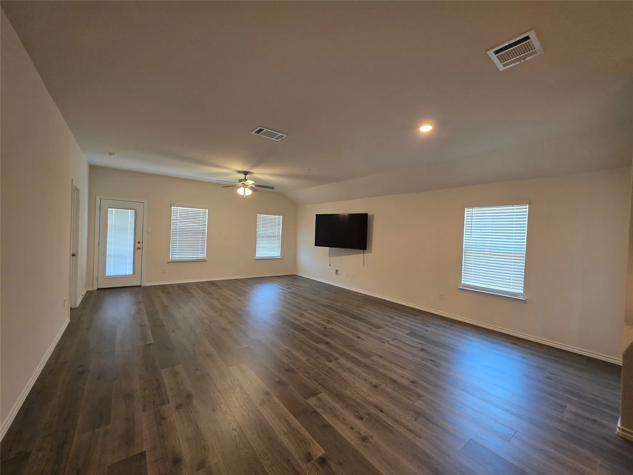 Spacious room featuring wood-finish flooring, a vaulted ceiling, recessed lighting, and a ceiling fan