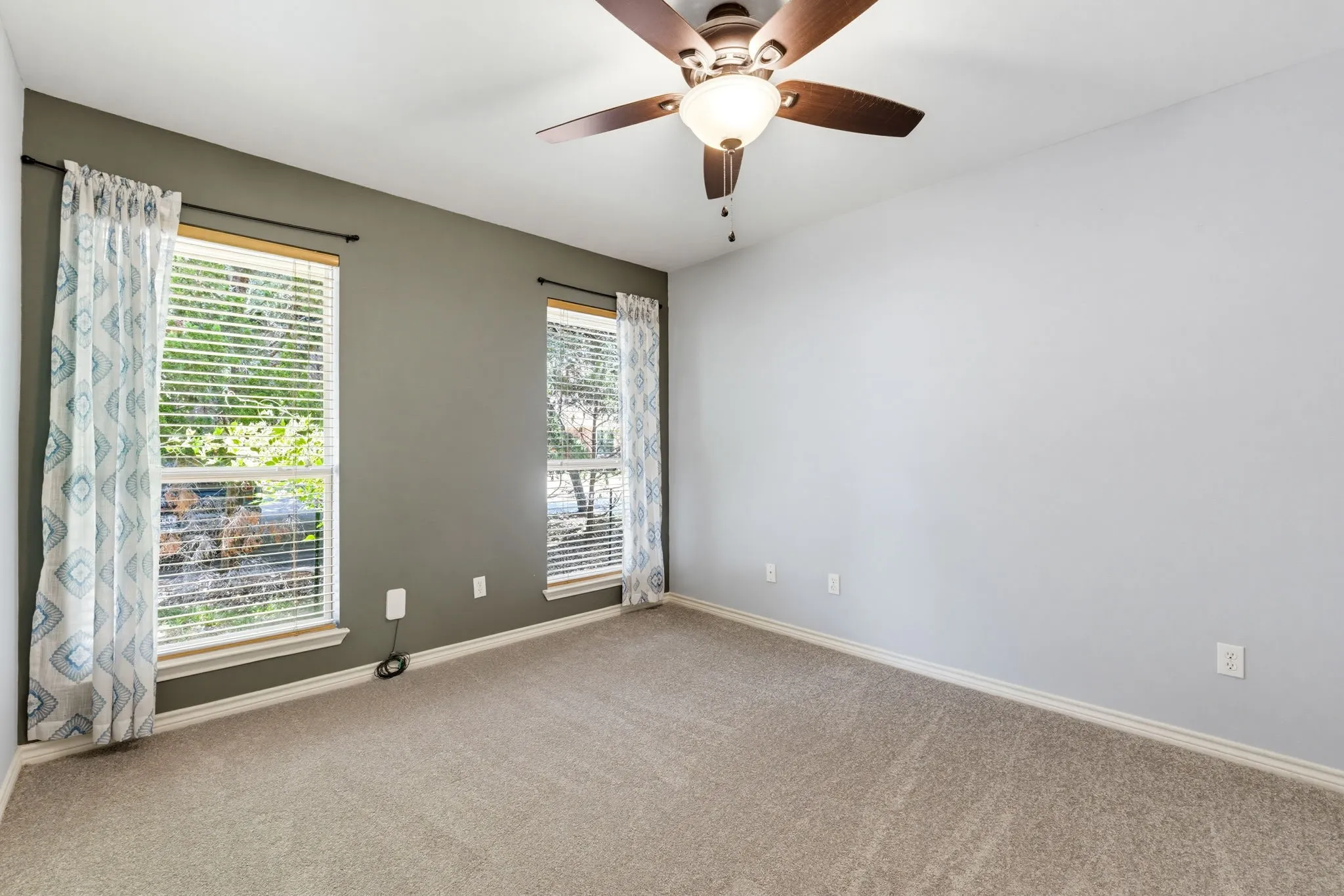 Recessed lighting, ceiling fan with wood-finish blades, two windows with blinds, and neutral carpeting