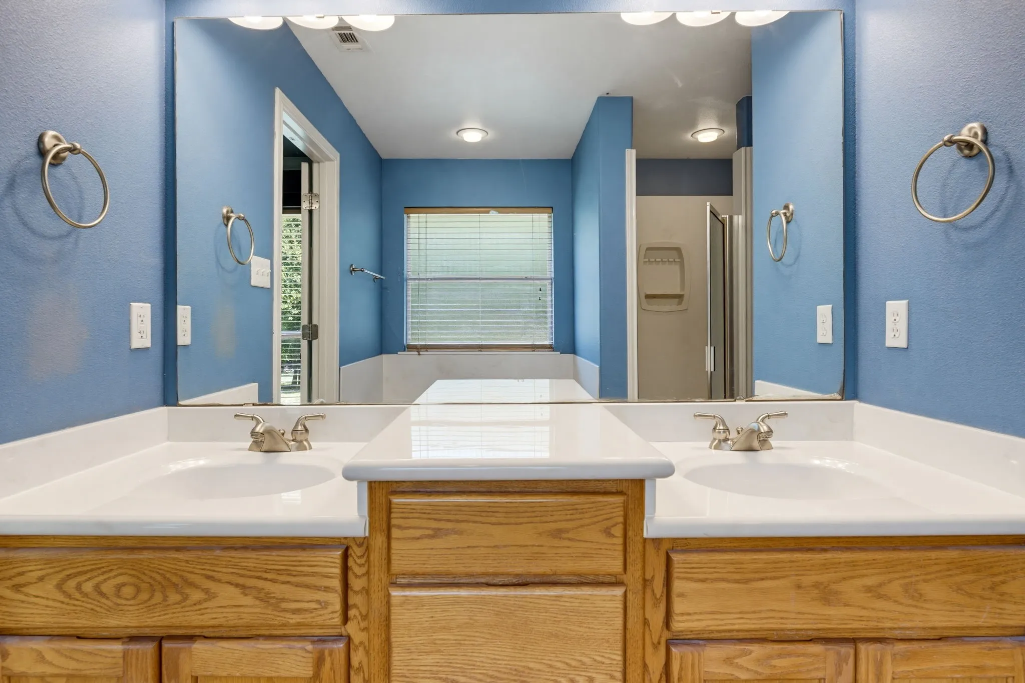 Double vanity with integrated sinks, wood-finish cabinetry, and brushed nickel fixtures
