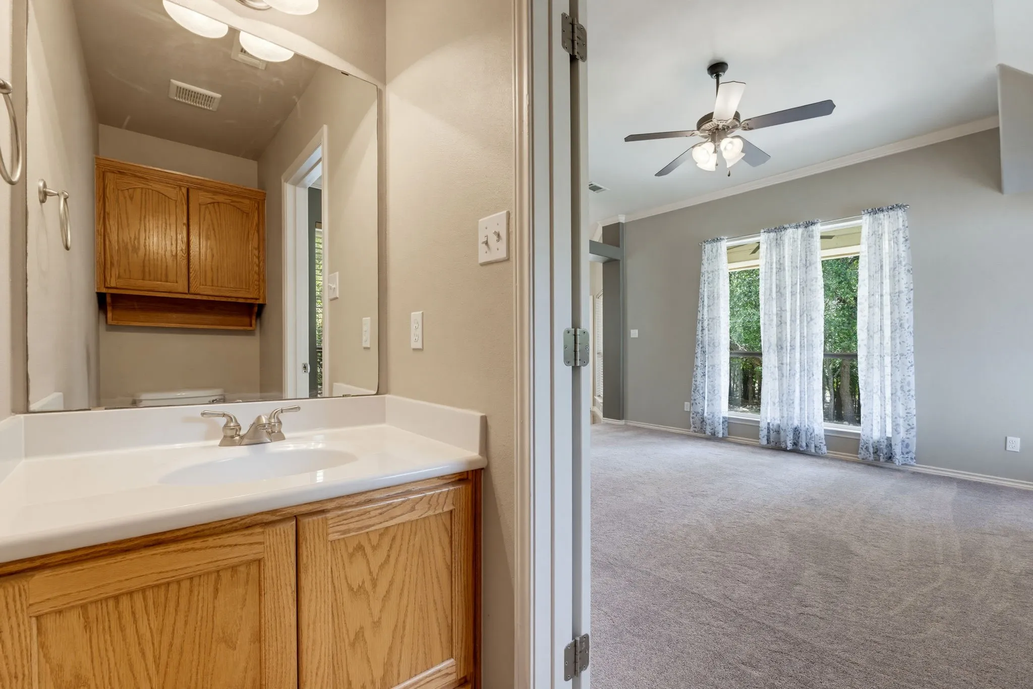 Bathroom vanity with light wood cabinetry and white countertop