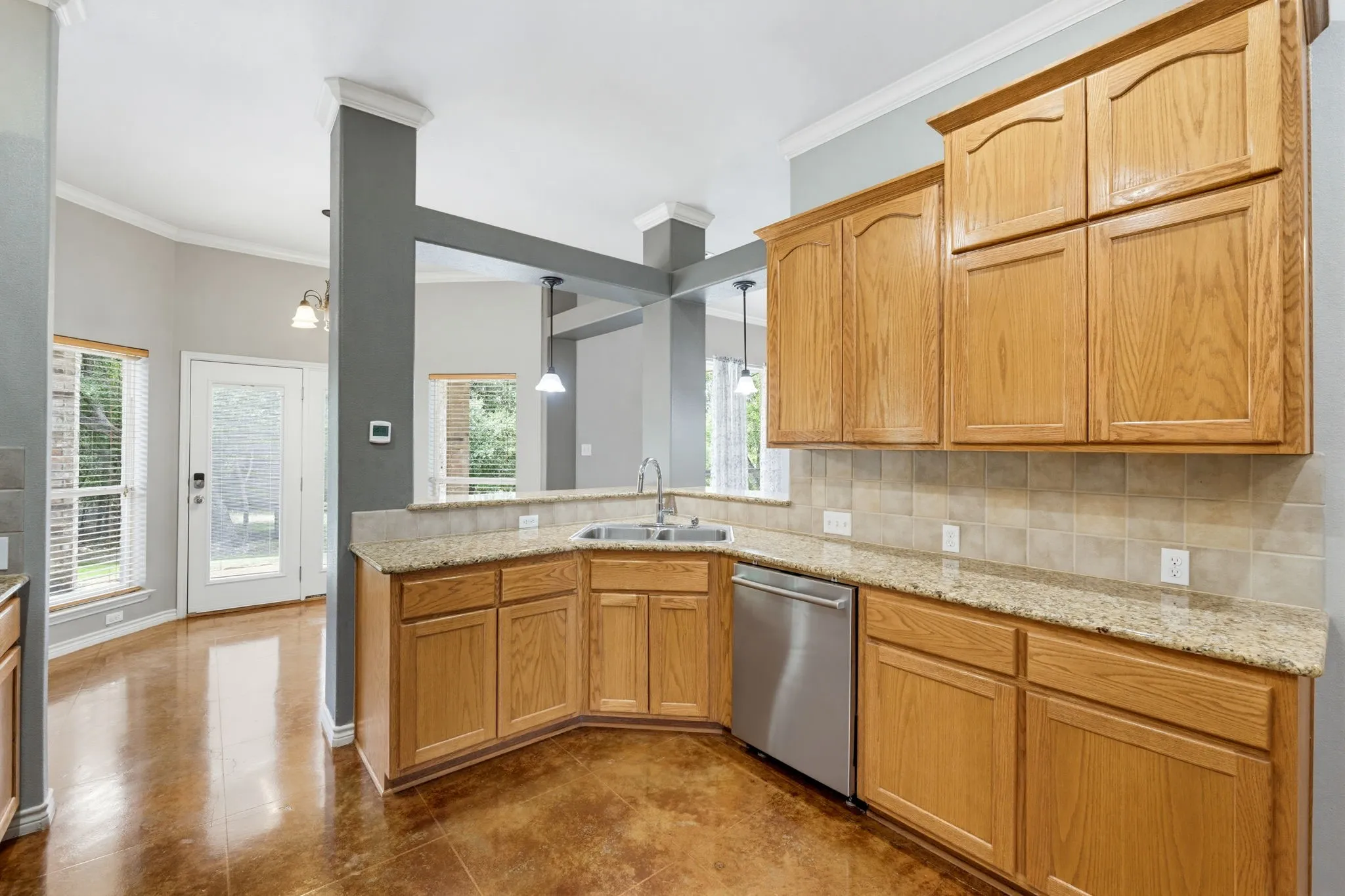 Kitchen featuring wood cabinetry, light-toned countertops, a tile backsplash, and a stainless steel dishwasher