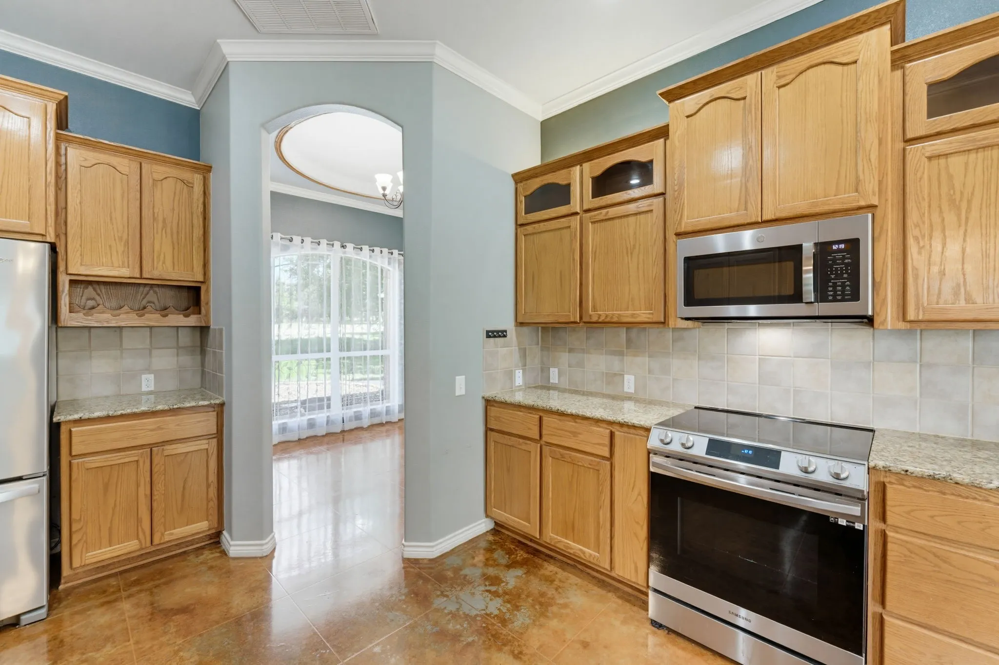 Kitchen featuring wood cabinetry, stainless steel appliances, granite-style countertops, and a tiled backsplash