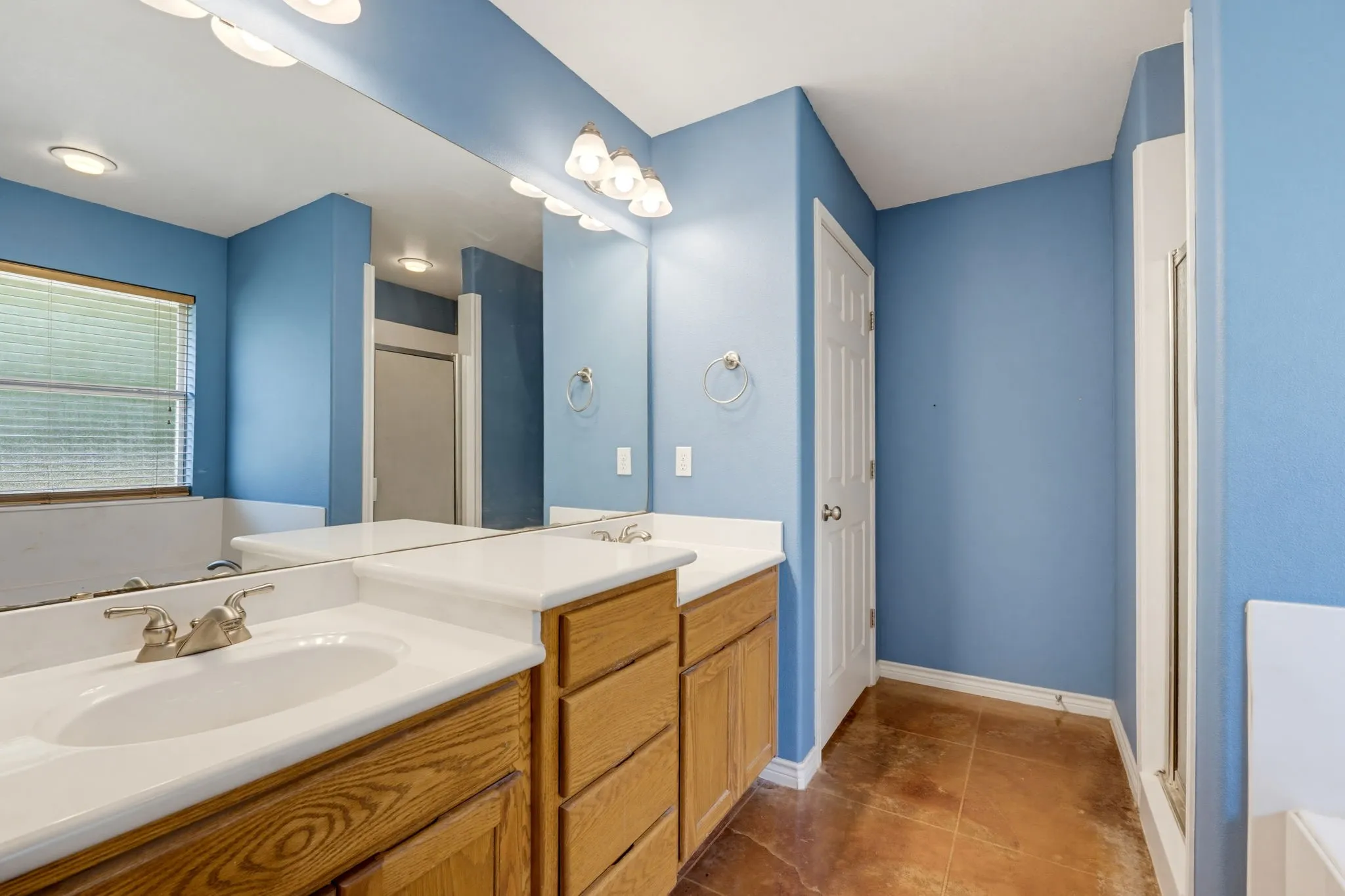 Dual vanity with wood-finish cabinetry, integrated sinks, and brushed nickel faucets