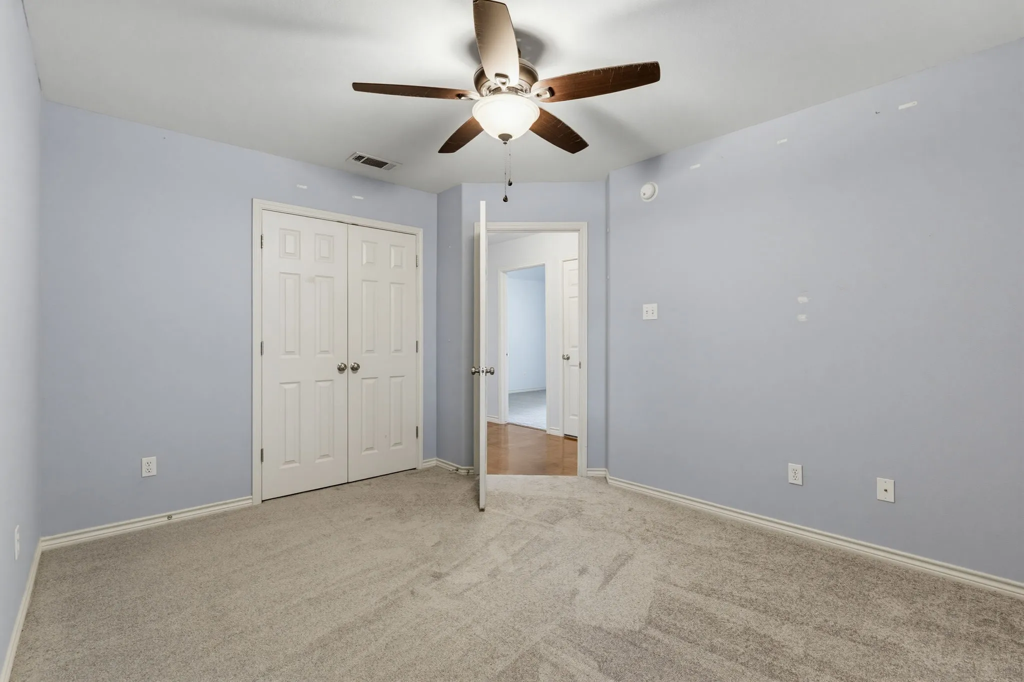 Ceiling fan with light fixture, light gray carpet flooring, white trim, white paneled doors, and light blue wall paint