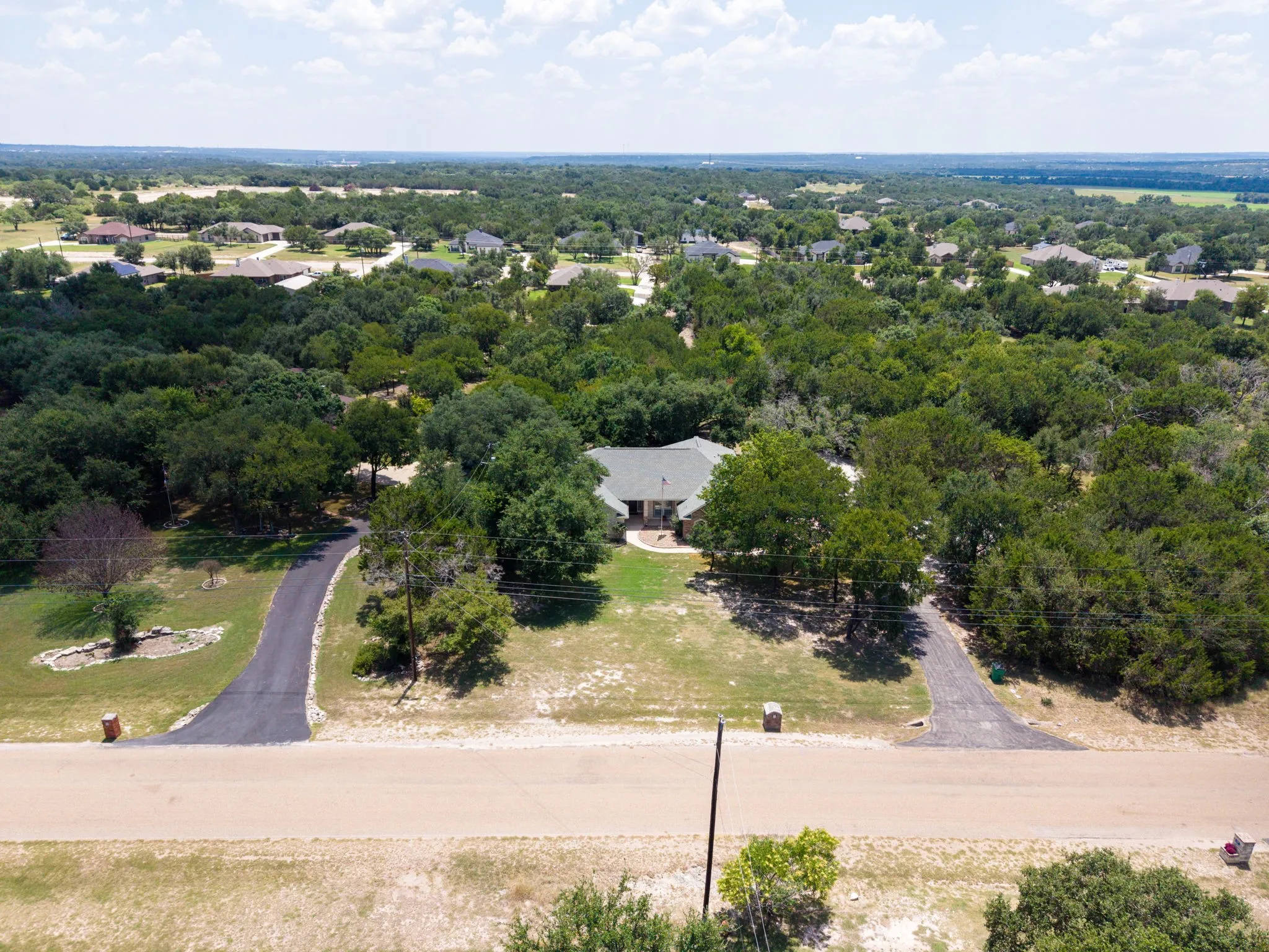 Expansive tree canopy surrounding the property with a residential structure featuring a gray roof