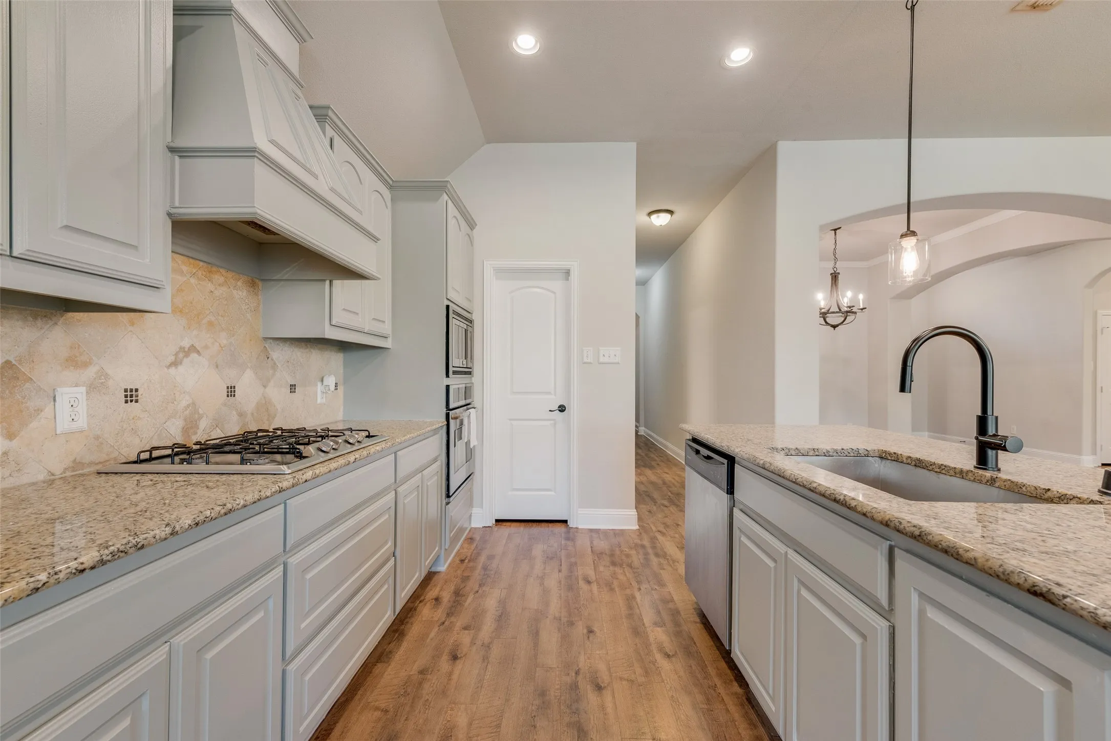Chef's kitchen featuring white cabinetry with shaker-style doors, granite countertops, stainless steel gas cooktop, and a large center island with seating