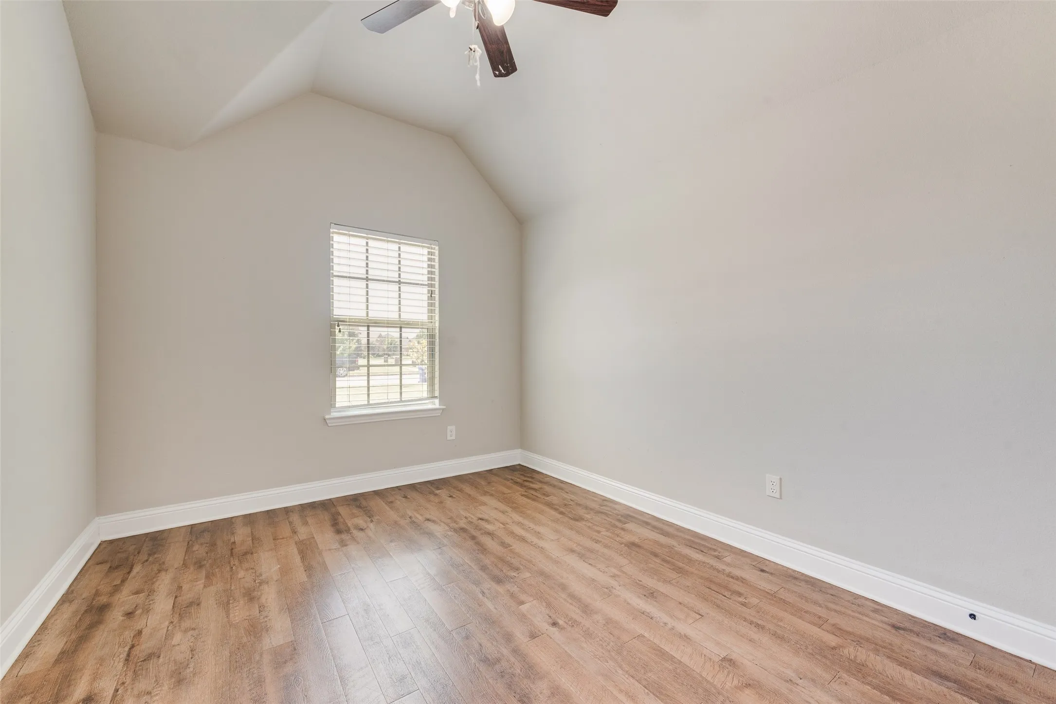 Vaulted ceiling with a ceiling fan, wood-finish flooring, and a window with blinds