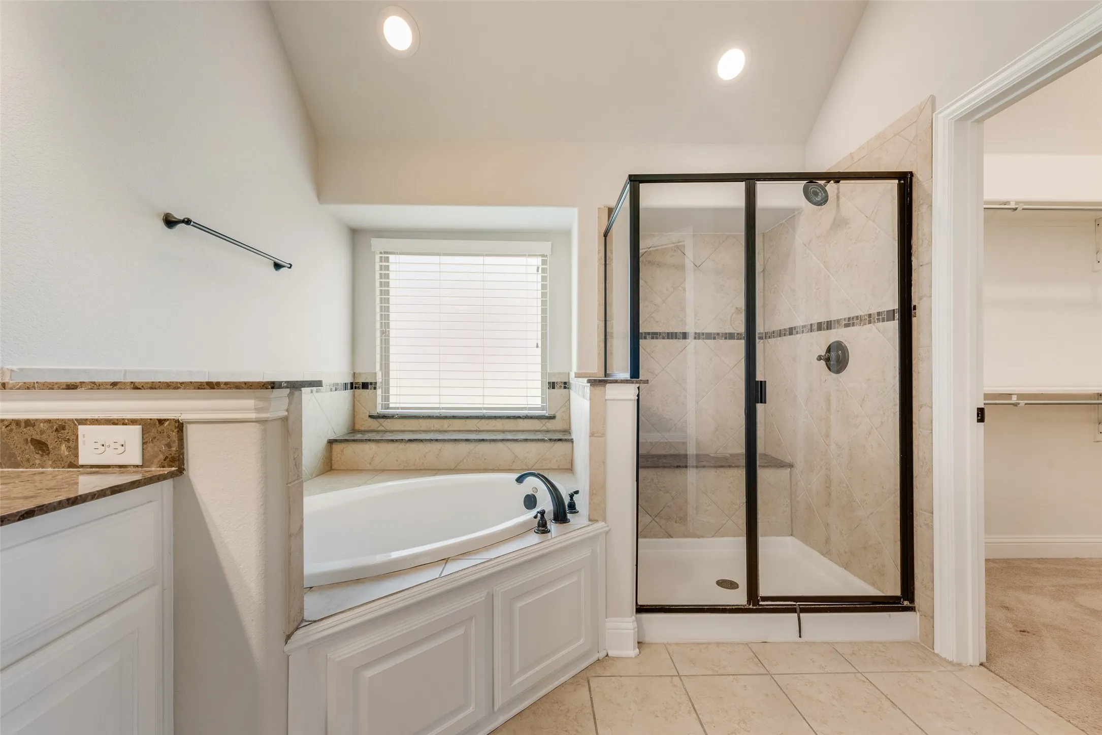 Corner soaking tub with a tiled surround, separate shower enclosure with a built-in bench, and a vanity with a countertop