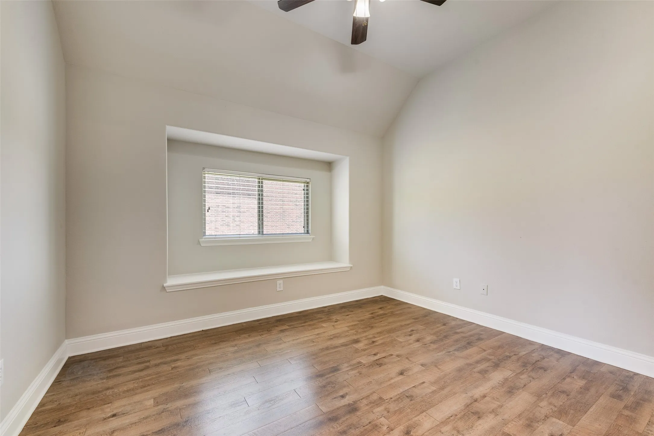 Vaulted ceiling with a ceiling fan, wood-finish flooring, recessed window, and white trim
