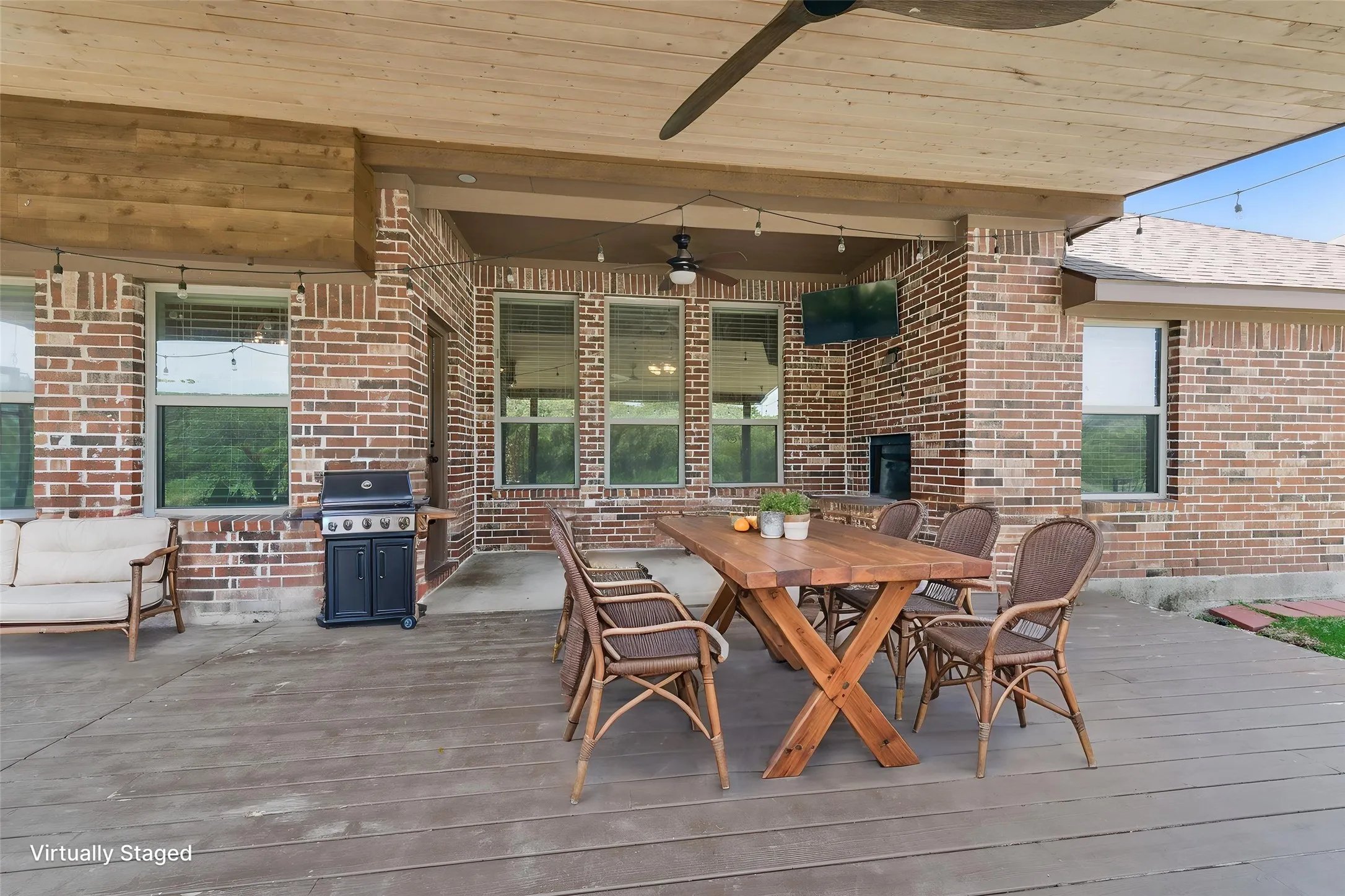 Virtually staged. Expansive covered patio featuring a wood-finish ceiling, exposed beams, brick exterior, and a built-in outdoor grill area
