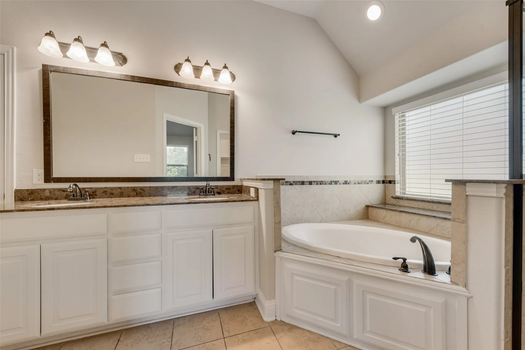 Dual vanity with a stone countertop and integrated sinks, complemented by a large framed mirror
