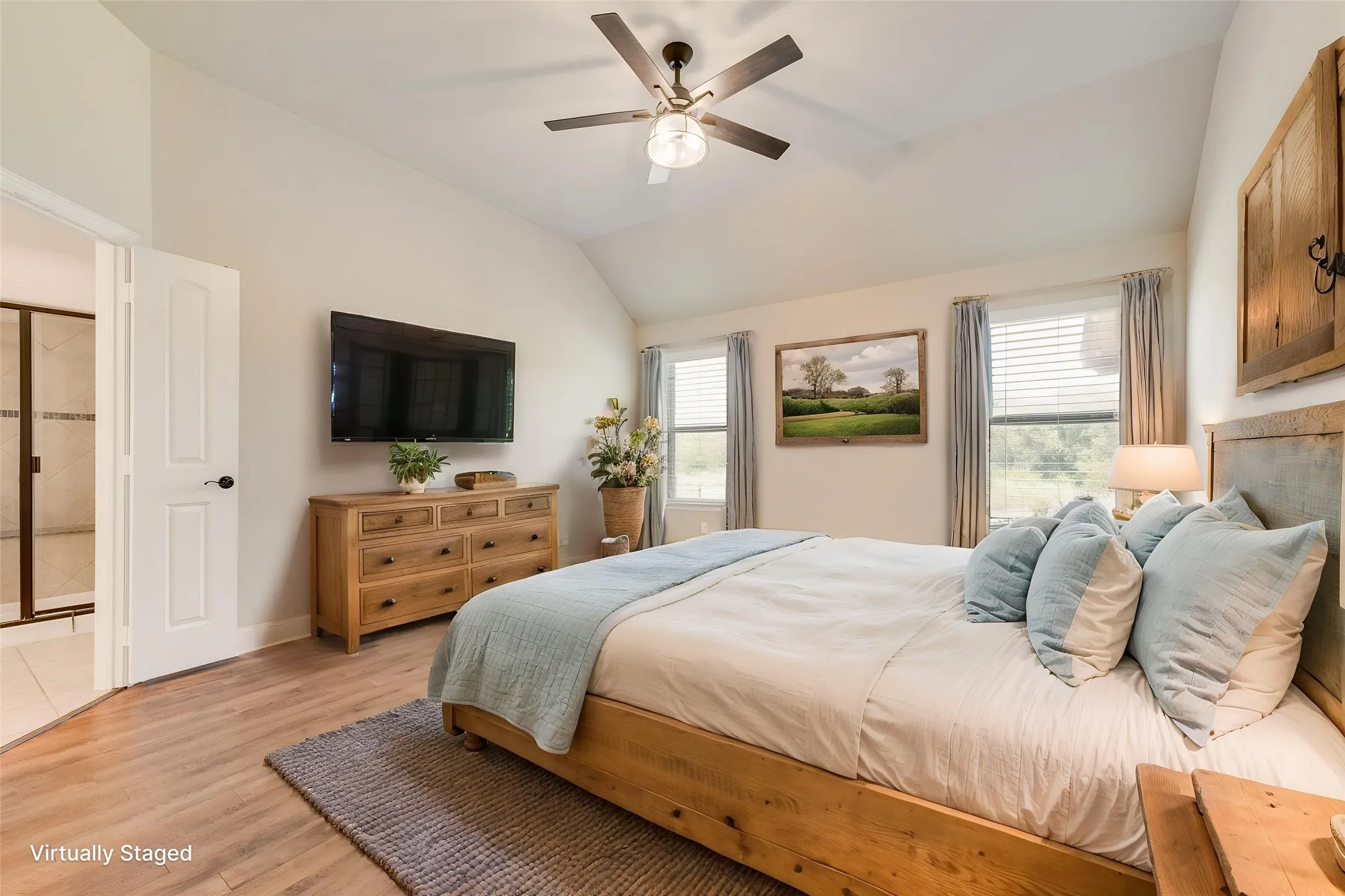 Virtually staged. Vaulted ceiling with a ceiling fan, wood-finish flooring, and multiple windows with blinds