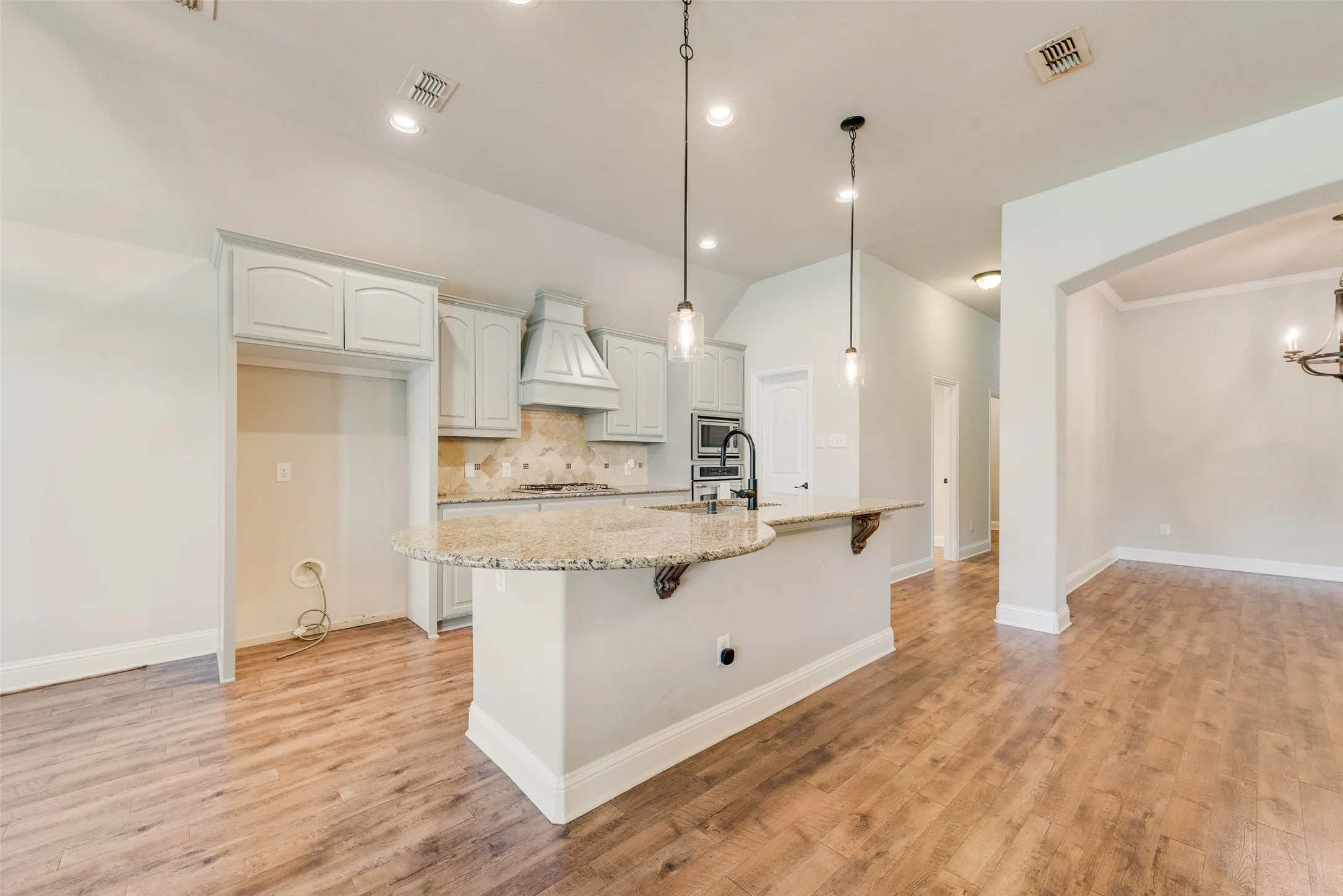Kitchen featuring light-toned cabinetry, light-colored countertops, a tile backsplash, and wood-finish flooring