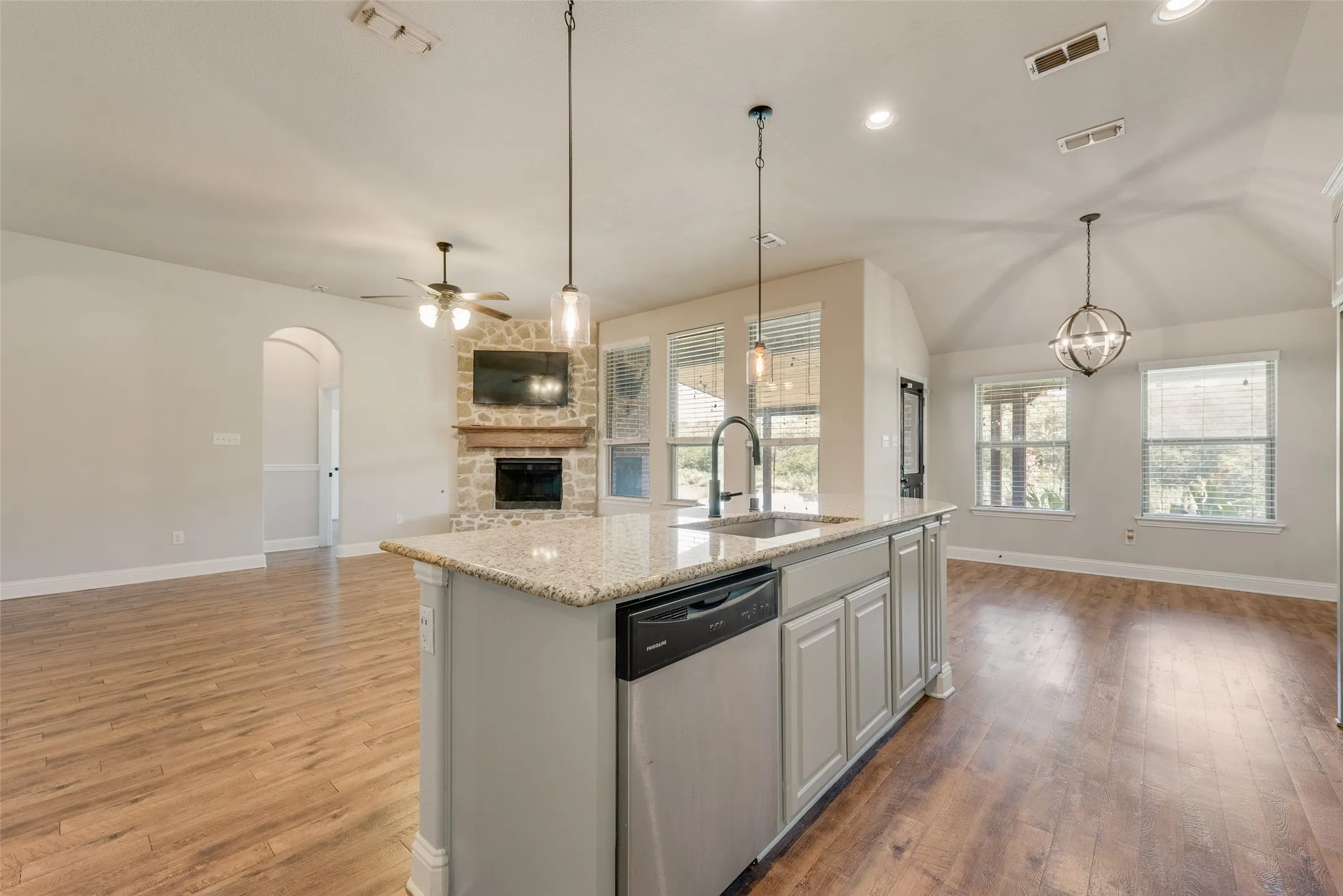 Kitchen island with granite countertop, integrated sink, and dishwasher