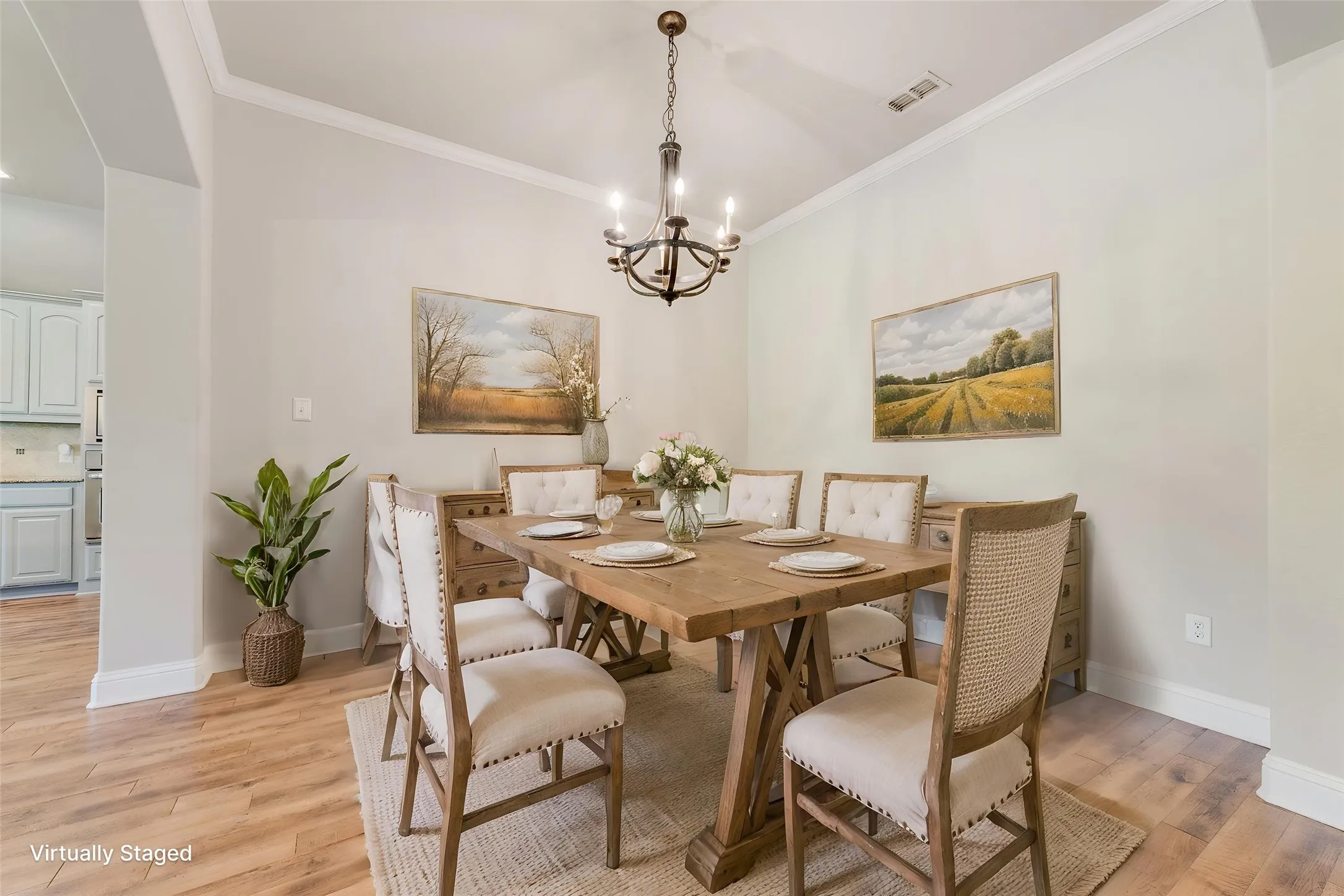 Virtually staged. Vaulted ceiling with crown molding, wood-finish flooring, and a chandelier lighting fixture