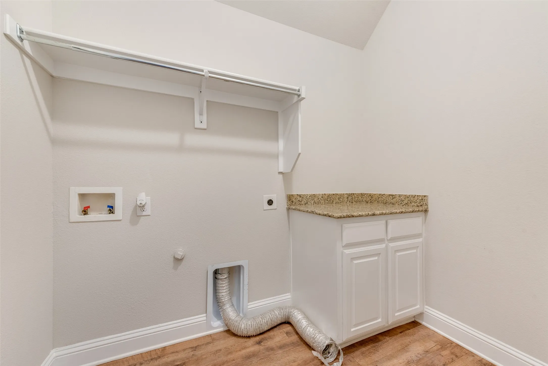 Utility room featuring white painted cabinetry, wood-finish flooring, and metal shelving