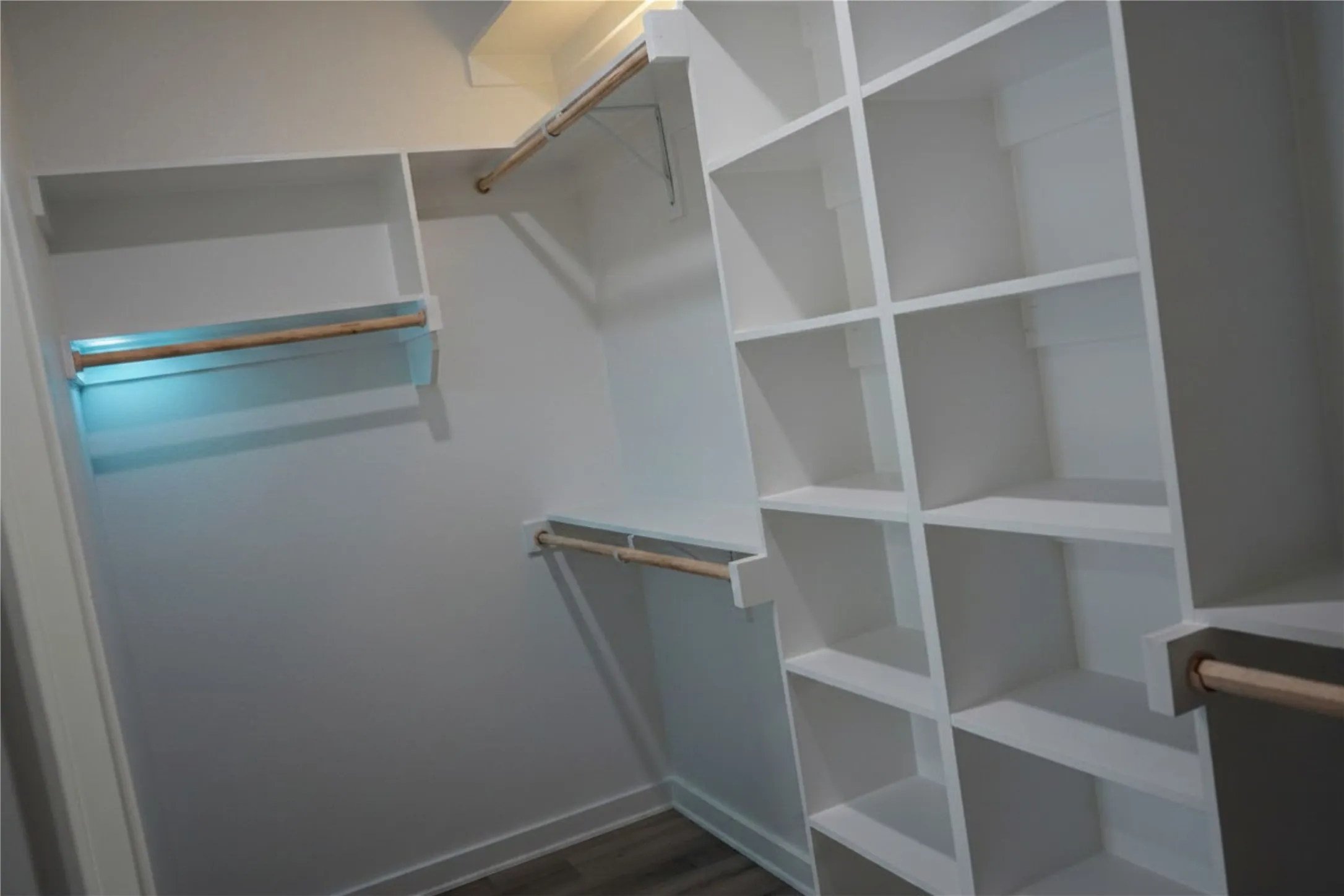 Built-in white shelving, multiple hanging rods, and integrated lighting