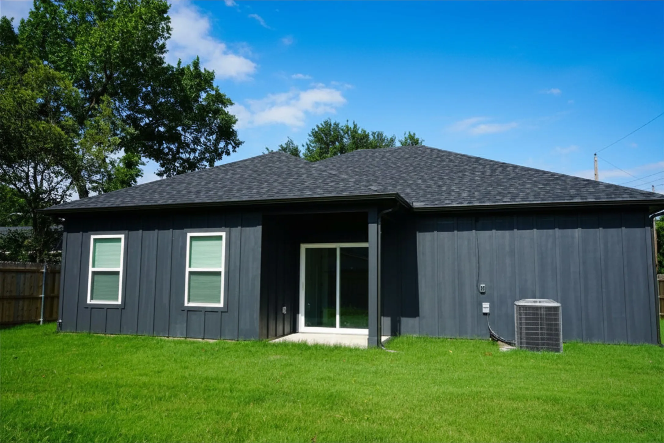 Dark-toned vertical panel siding exterior with white-framed windows and a dark shingle roof
