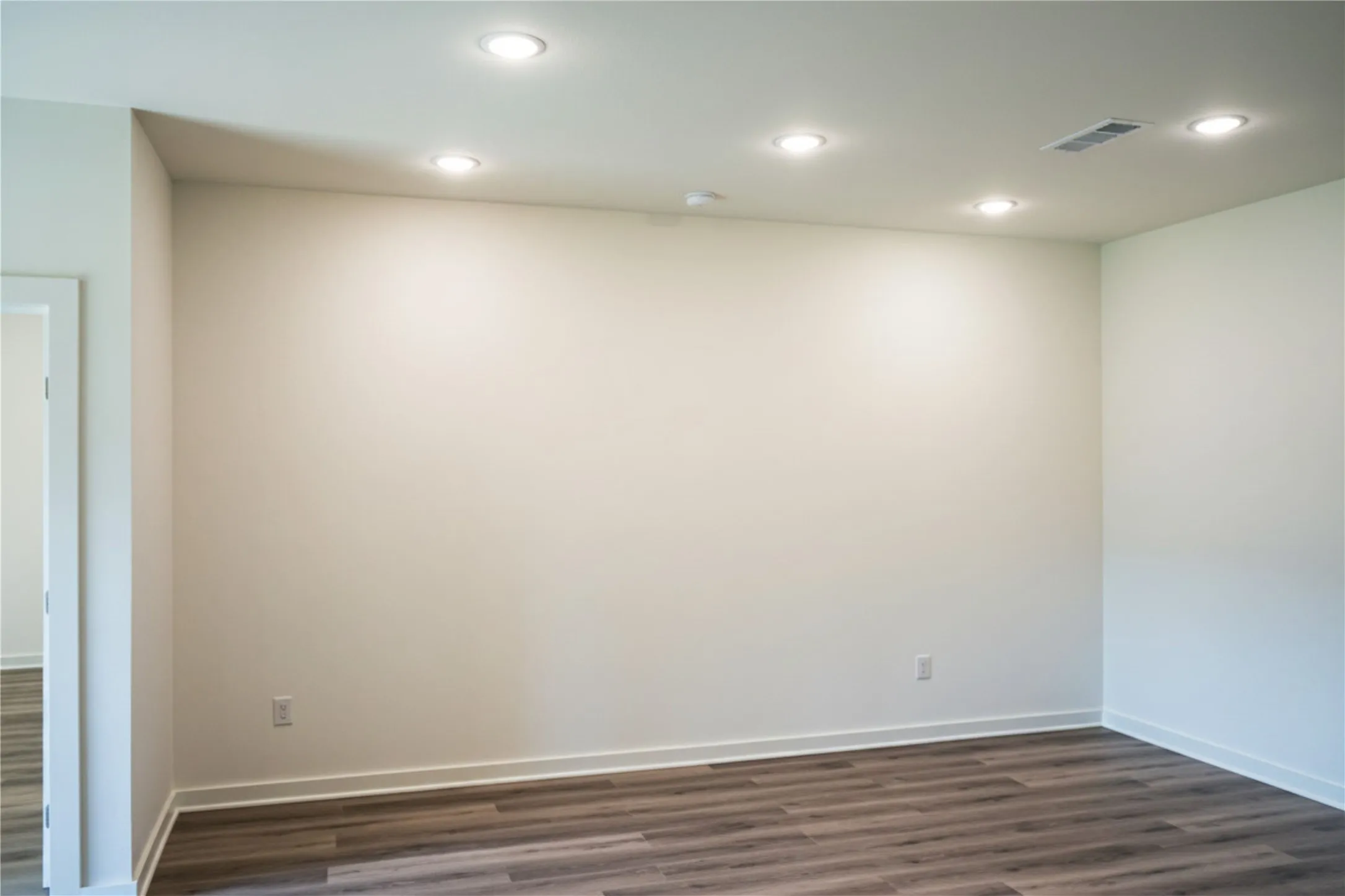 Wood-finish flooring, recessed lighting, and a white interior door