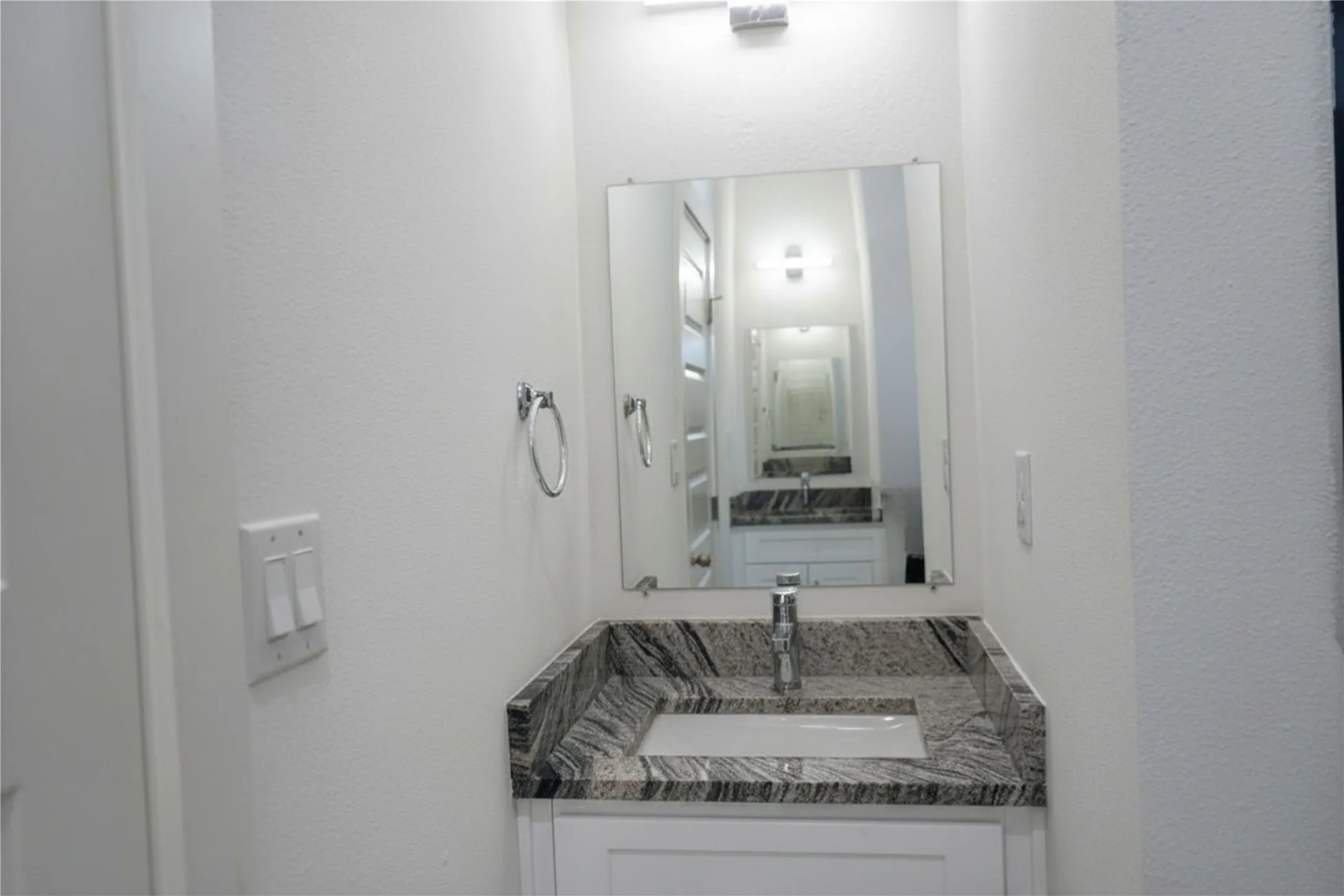Vanity with a granite countertop, undermount sink, and chrome faucet