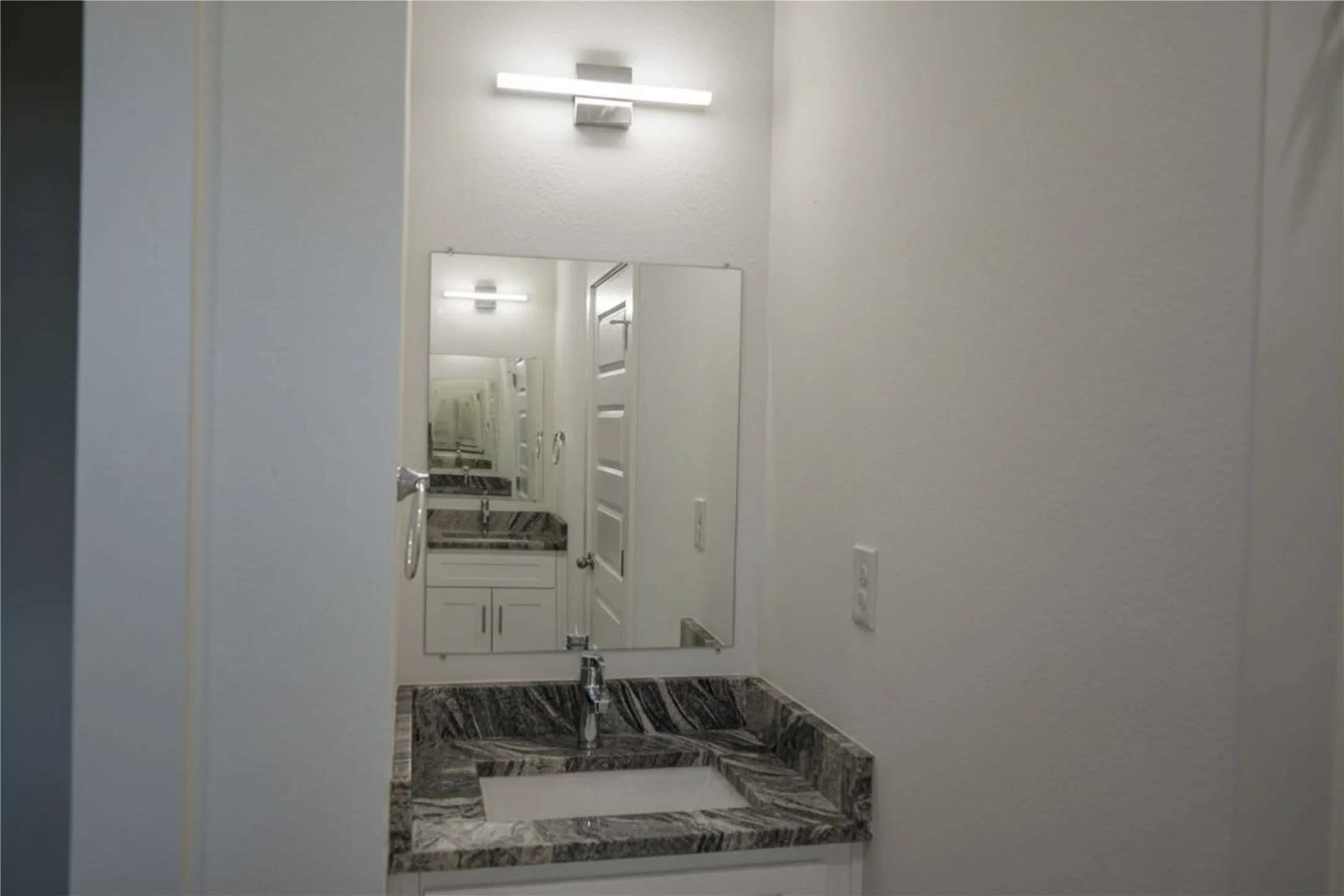 Vanity with granite countertop, integrated sink, and white cabinetry