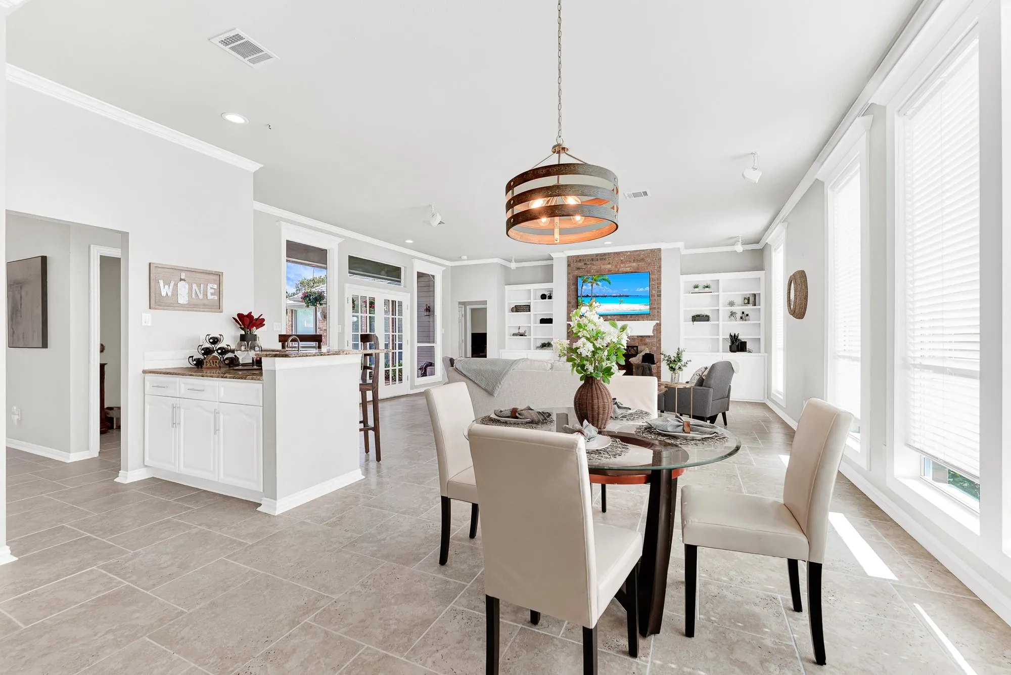 Floor-to-ceiling windows flood the informal dining area with morning sun, illuminating the adjacent wet bar. Savor a quiet cup of espresso here as natural light fills the open floor plan.