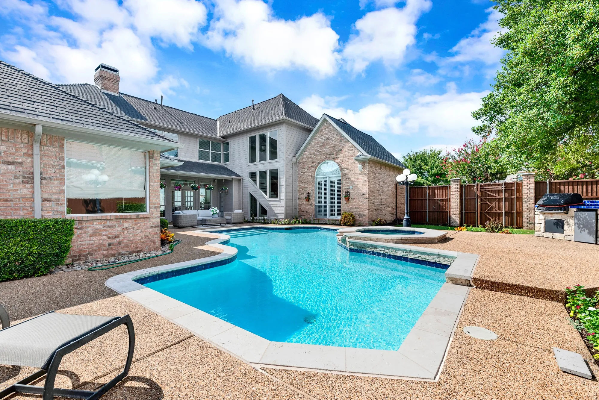 A sparkling freeform pool glistens under bright blue skies framed by rich brick gables and a sprawling aggregate deck. Dip your toes into refreshing waters while soaking up golden sunbeams on warm summer afternoons.