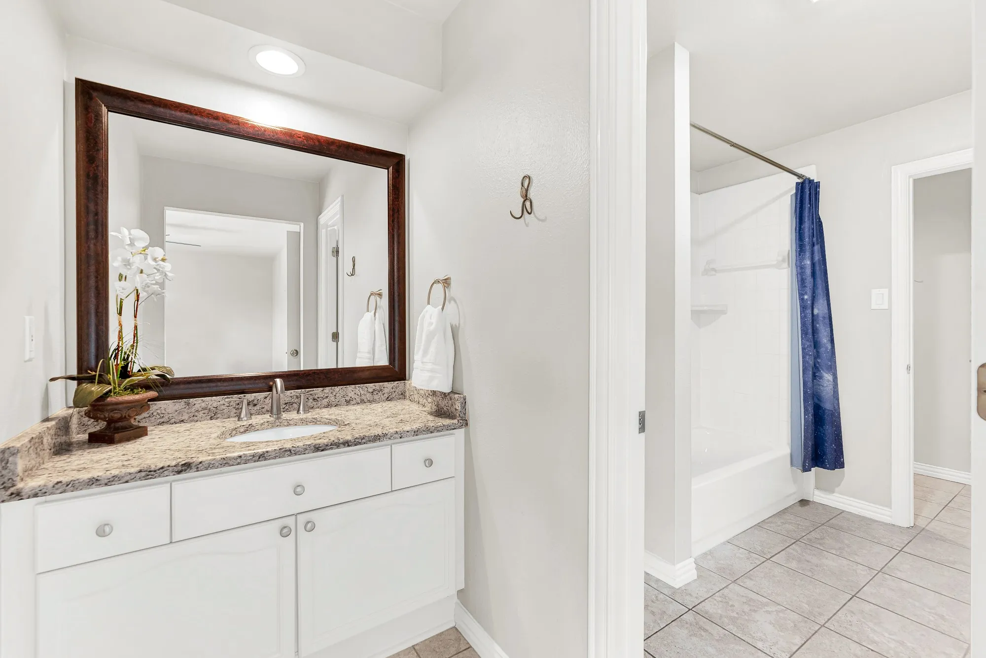 A wide single vanity pairs with classic square floor tile leading into a private tub area. Children can wind down with a warm bubble bath right before reading bedtime stories.