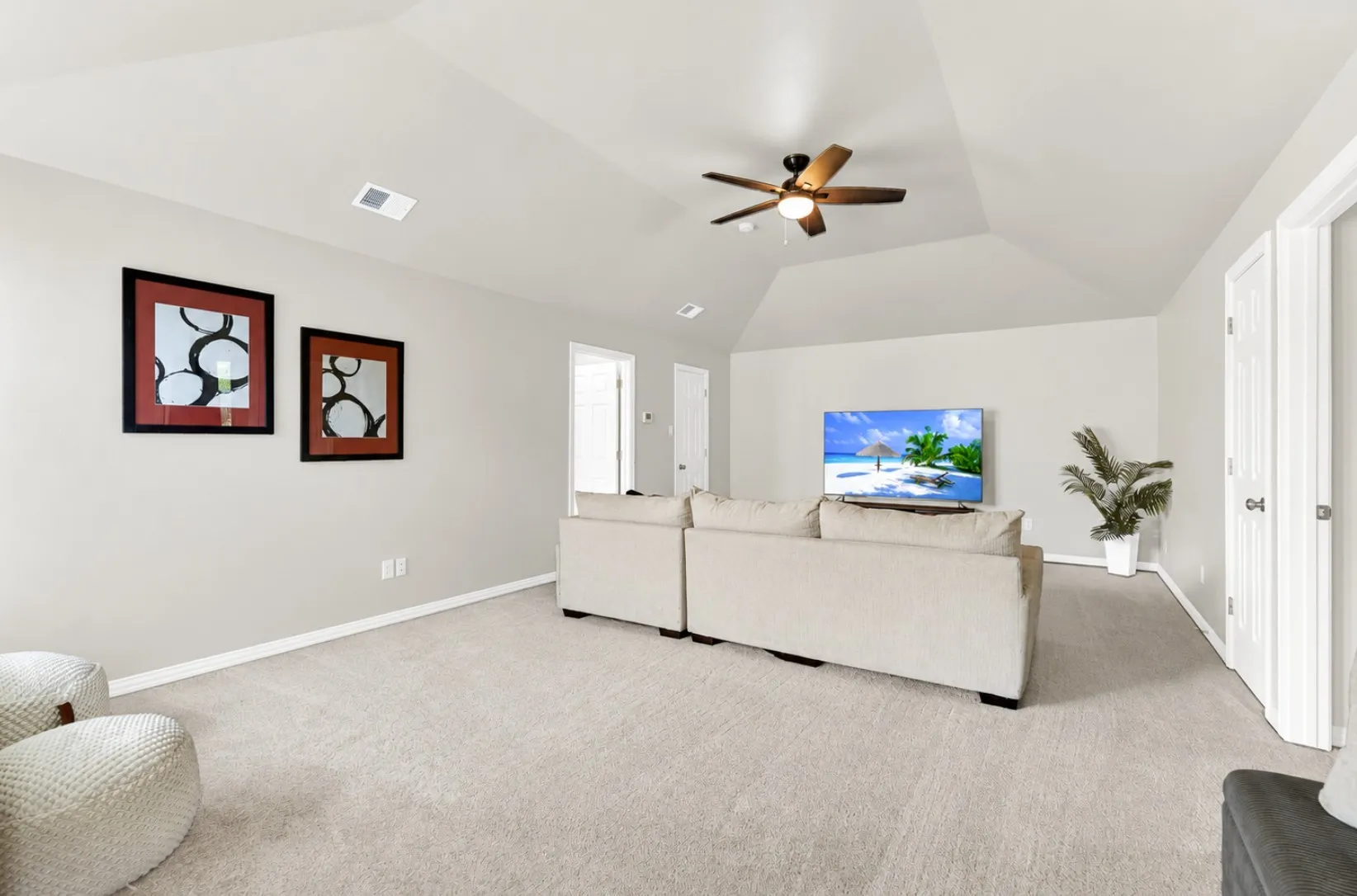 A high vaulted ceiling creates an expansive, airy feel illuminated by a central dark fan light fixture. Kids can spread out across plush carpeting for gaming sessions or movie marathons on quiet rainy afternoons.