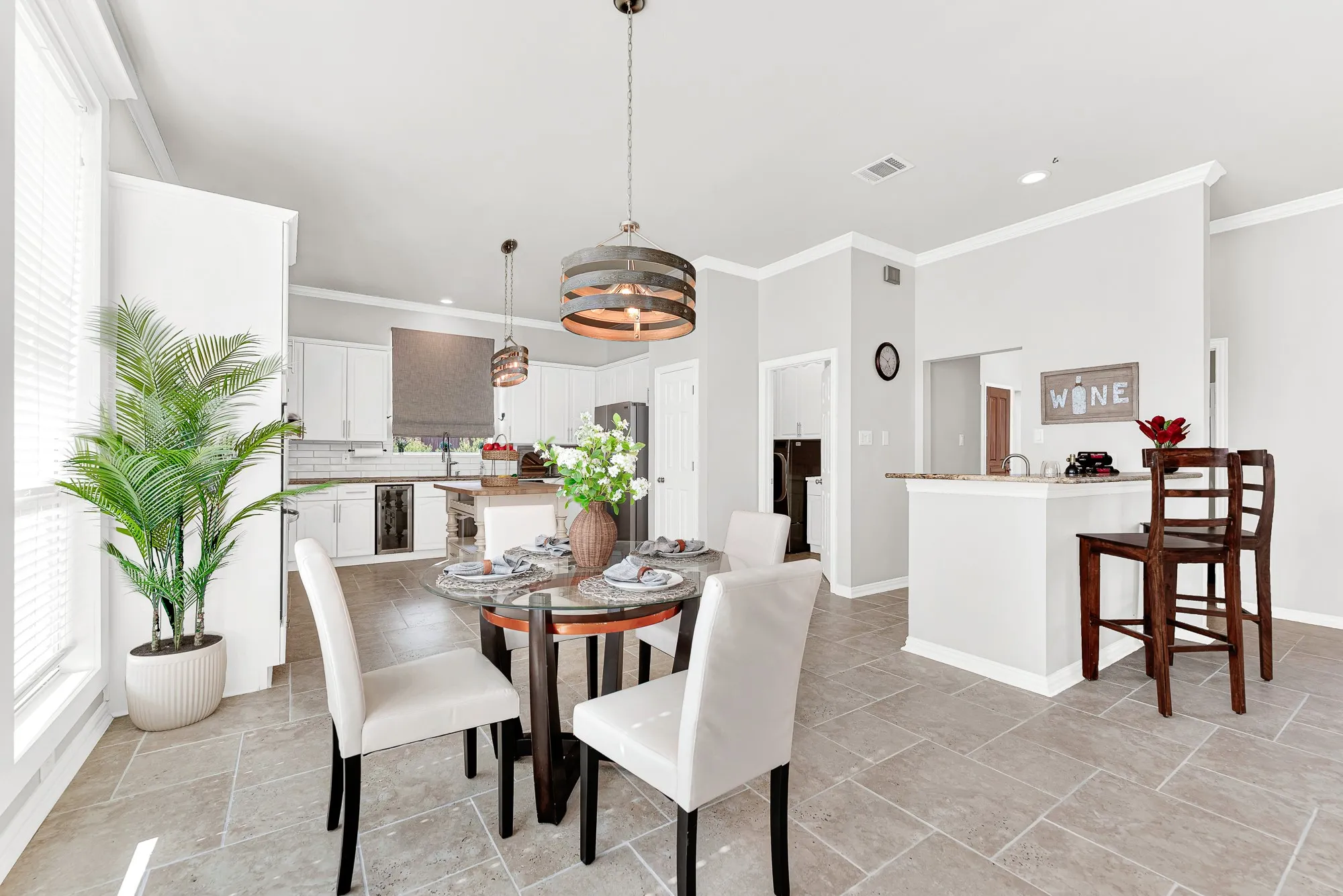 A stylish drum pendant centers the casual dining space, bridging the gap between the kitchen and raised wet bar seating. Enjoy casual weekend lunches right by the window with a full view of the main workspace.