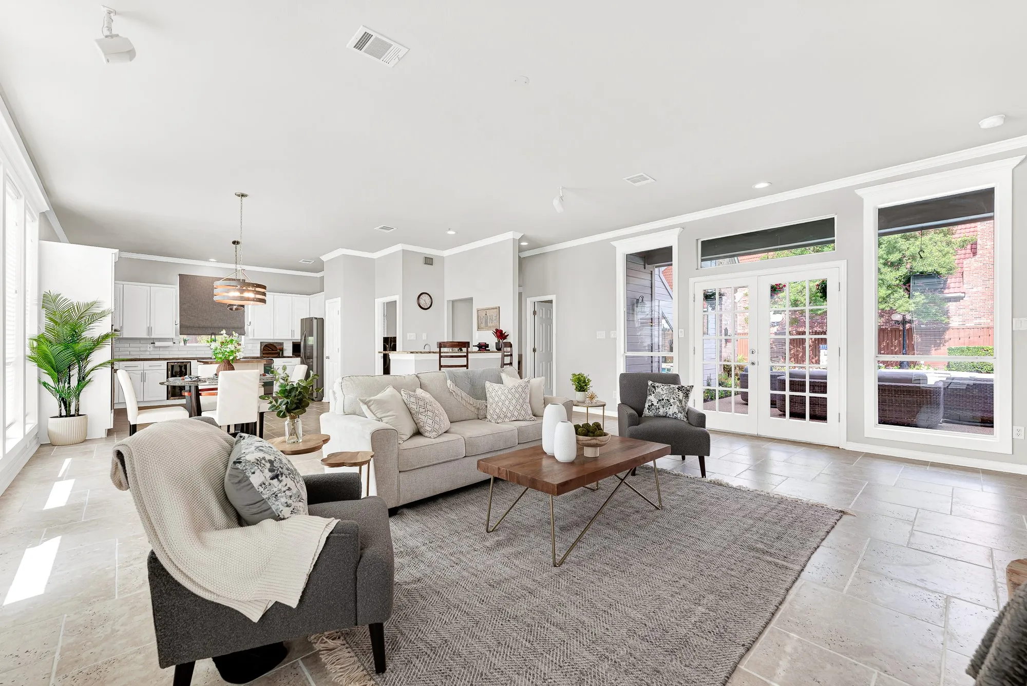 Glass patio doors open onto the pool deck, drawing natural light deep across neutral tile flooring into the open kitchen beyond. Walk straight inside from a refreshing dip to grab a quick summer snack.