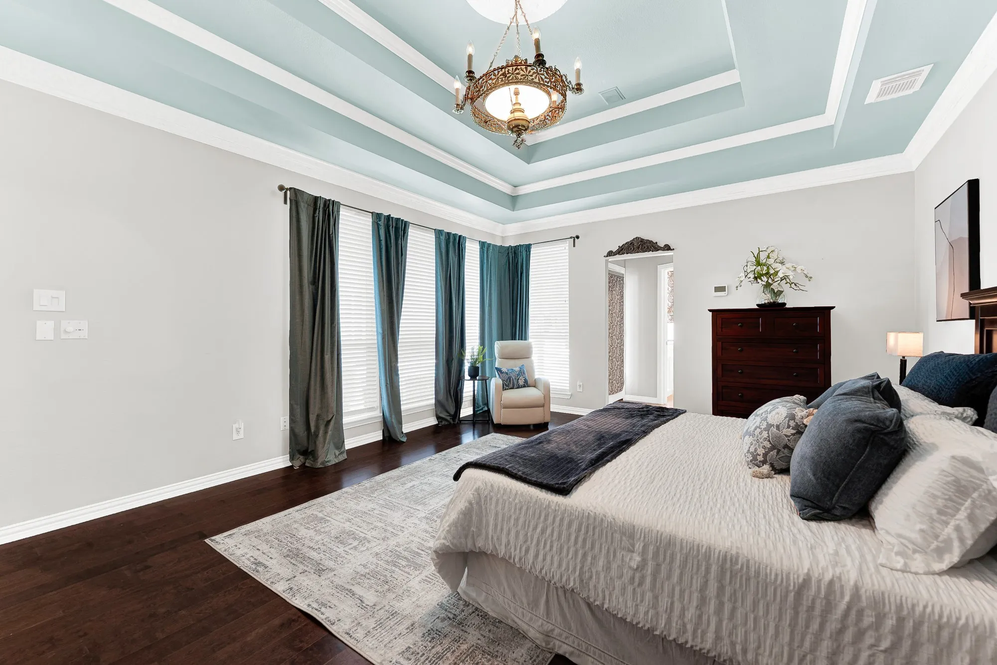 A row of tall windows illuminates rich, dark hardwood floors that contrast beautifully against crisp white baseboards. Enjoy a quiet afternoon reading your favorite book while soft outdoor light filters through the blinds that can open to give serene pool views.